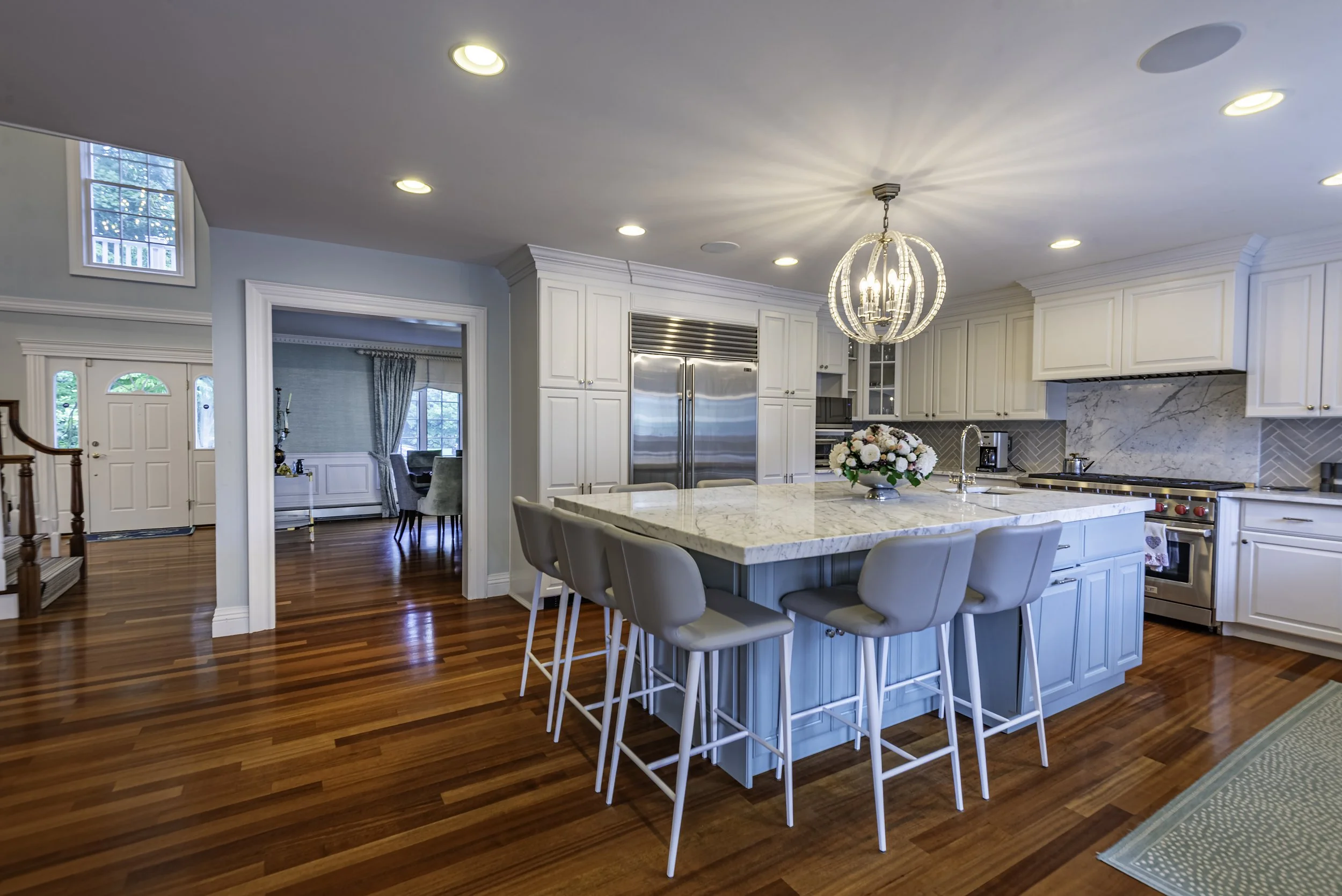 Professional real estate kitchen photography featuring a bright modern kitchen with marble countertops, designer lighting, hardwood floors, and open concept layout in New York.