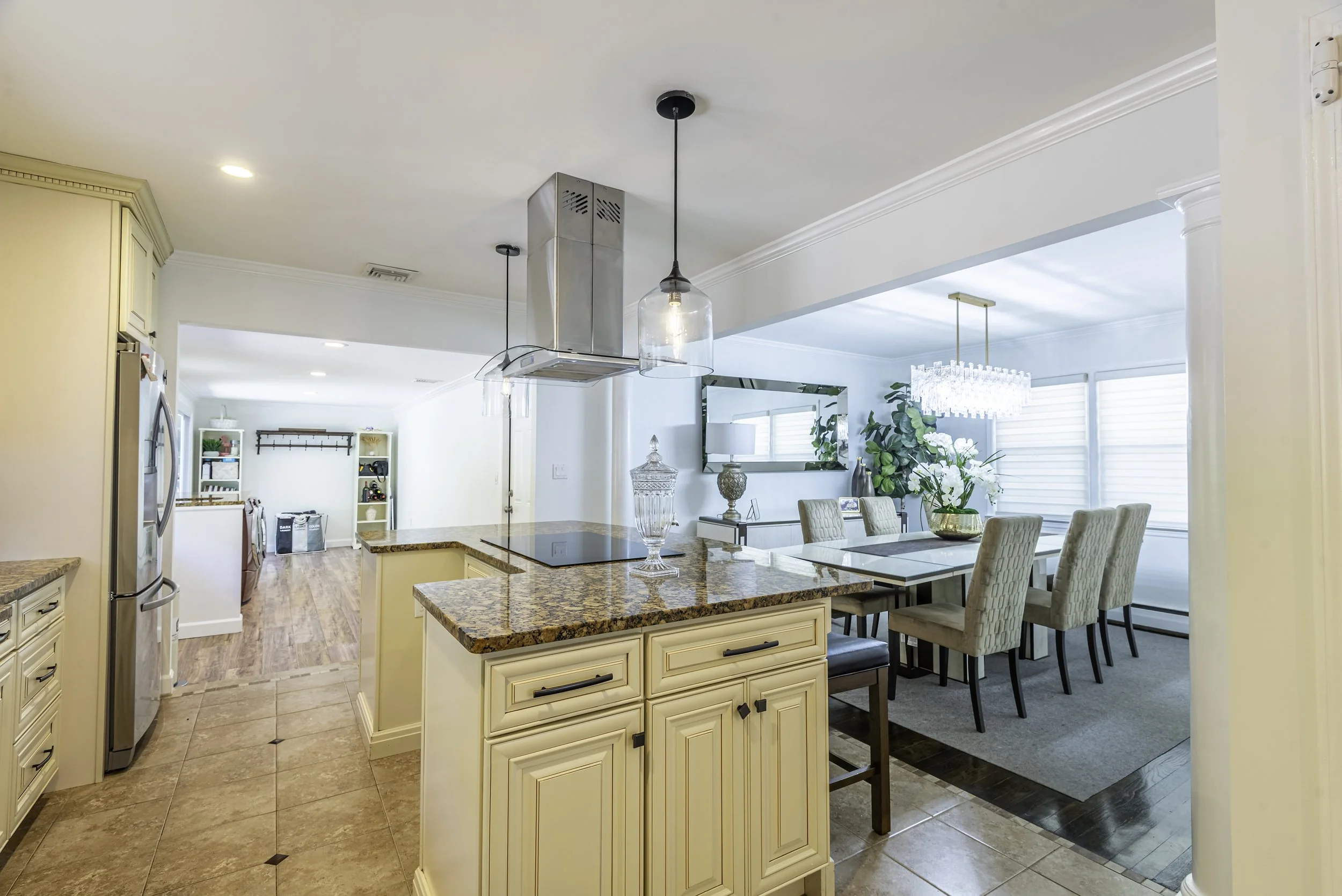 Professional interior real estate photo showcasing a bright kitchen with island and adjoining dining room.