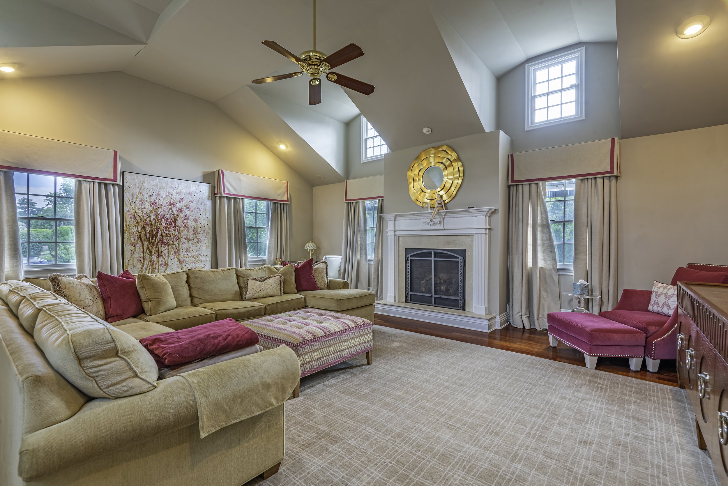 Luxury family room with fireplace, high ceilings, stylish furniture, and natural window light captured for professional real estate photography in New York.