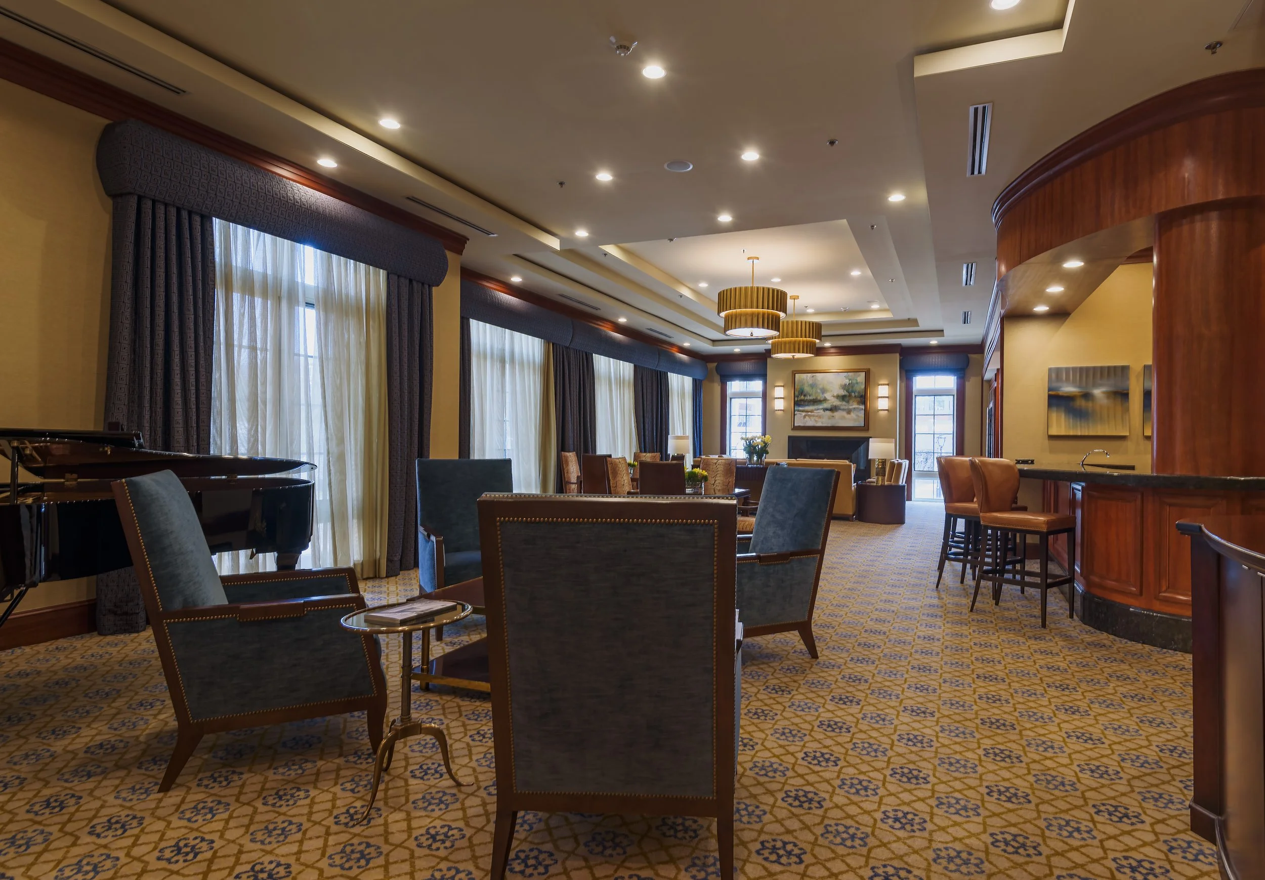 Luxury condominium lounge interior at the Ritz in Long Island featuring seating area, piano, bar, and architectural lighting design.
