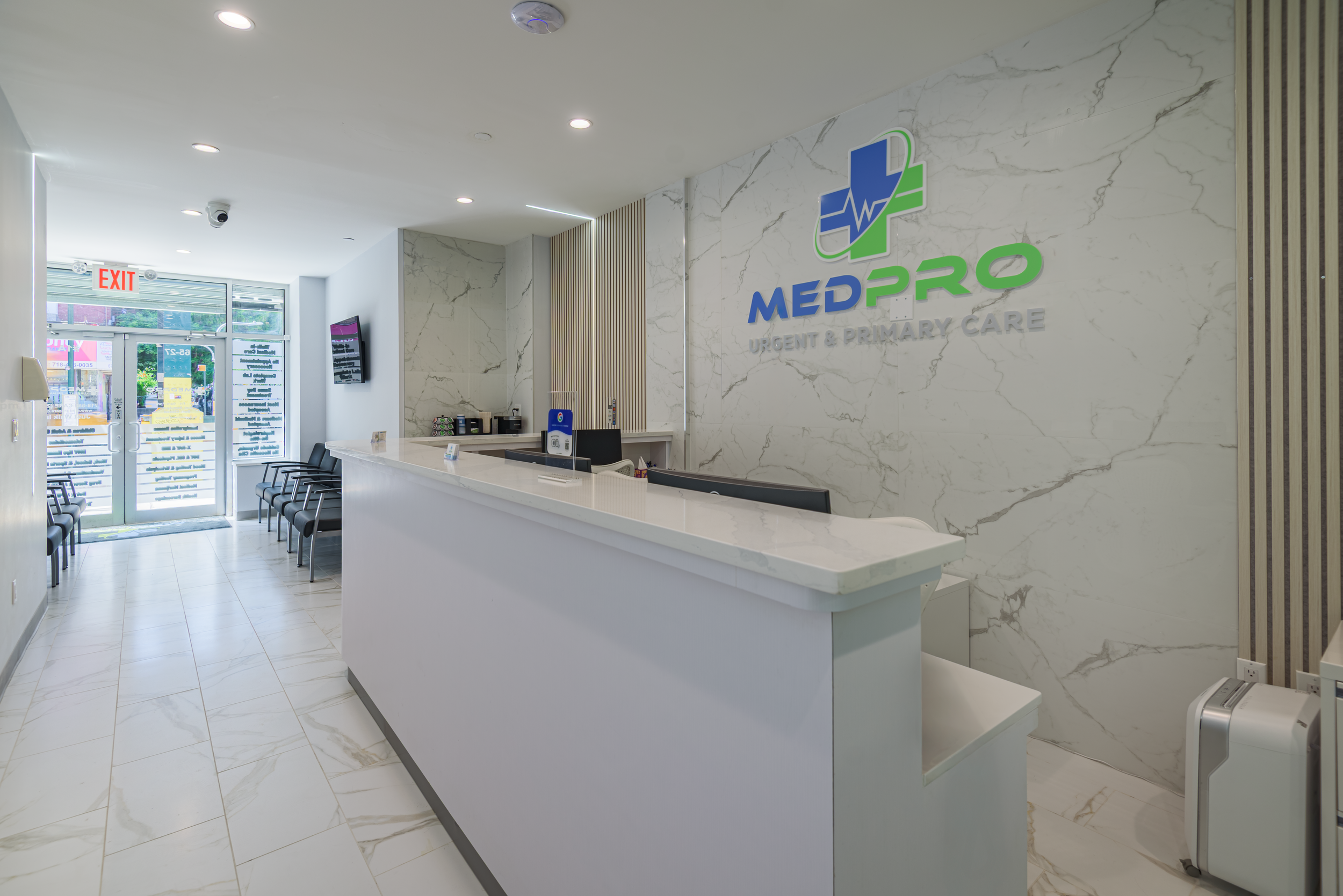 Architectural interior photograph of a modern medical clinic reception area featuring marble wall panels, custom reception desk, integrated lighting, and branded healthcare design, photographed in NYC serving Queens and Long Island.