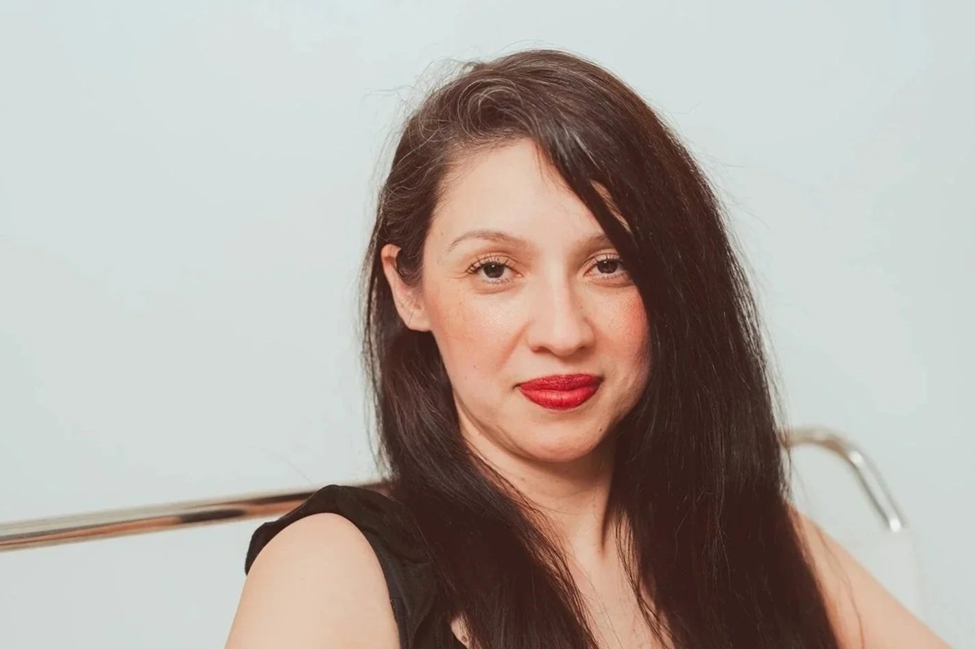 Cindy Chavez-Swenson, fundadora de R.O.S.C.A. Money Circle, viste un top negro sin mangas y sonríe levemente ante un fondo liso de color claro.