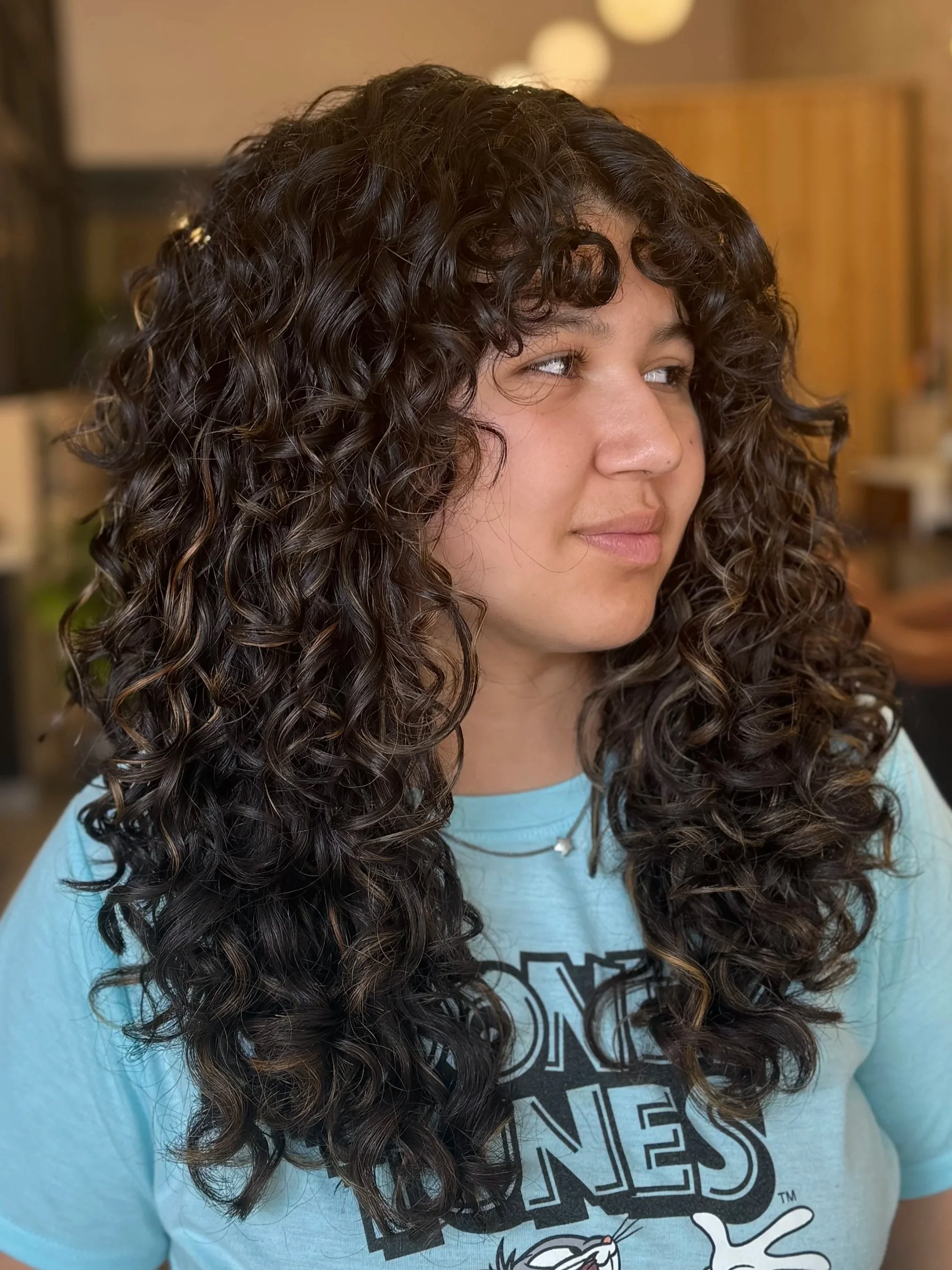 salon customer with beautiful coily hair looking too the left and smiling