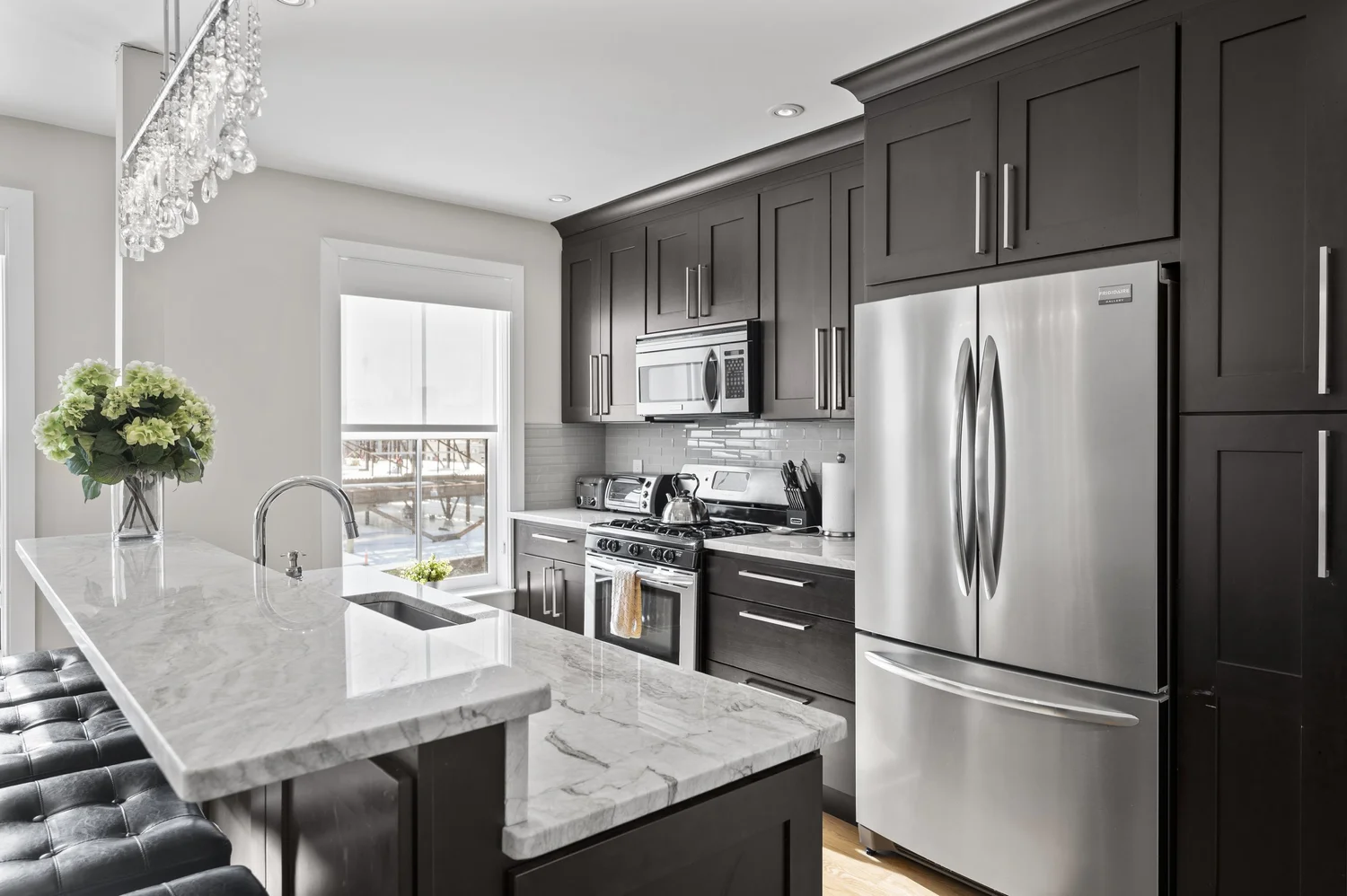 Kitchen with espresso cabinets, quartz island, and stainless appliances