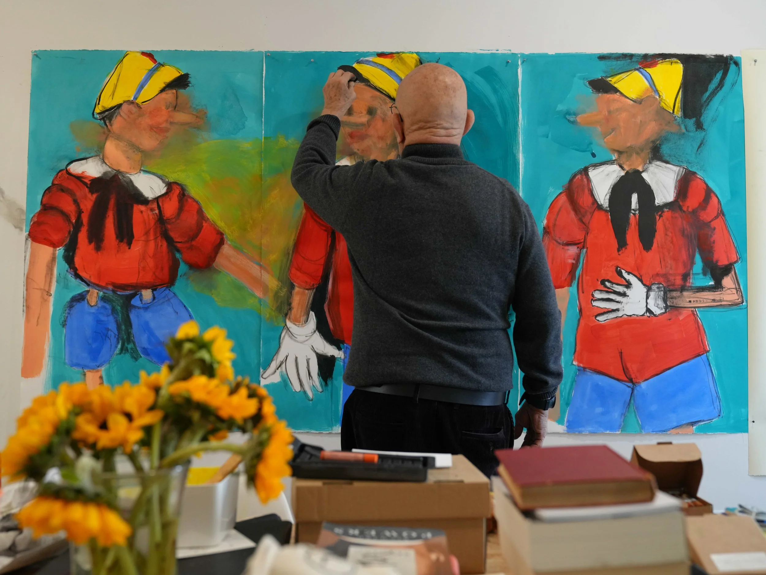 Artist Jim Dine in the studio working on three paintings of Pinocchio