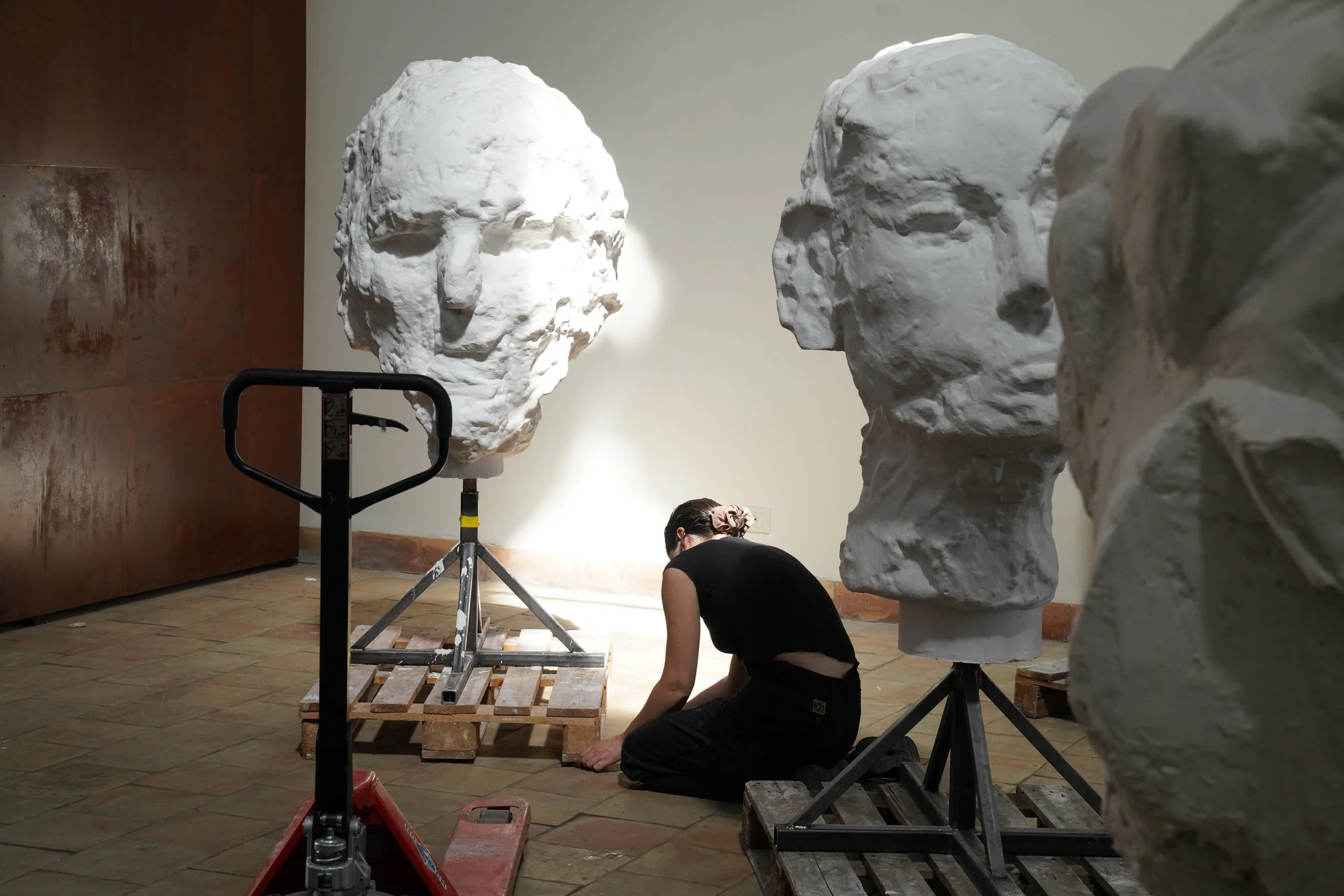Image of woman installing Images of Jim Dine's plaster heads in his new exhibition Elysian Fields