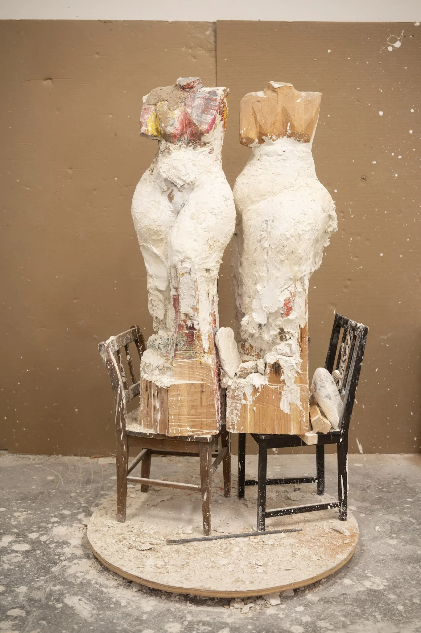 Two plaster female figures standing on chairs facing each other