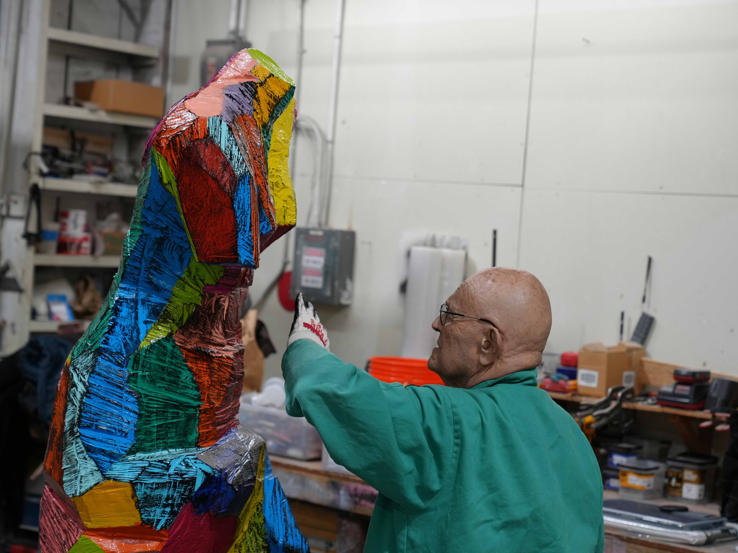 Artist Jim Dine in his studio wearing a green shirt and working on a colorful sculpture