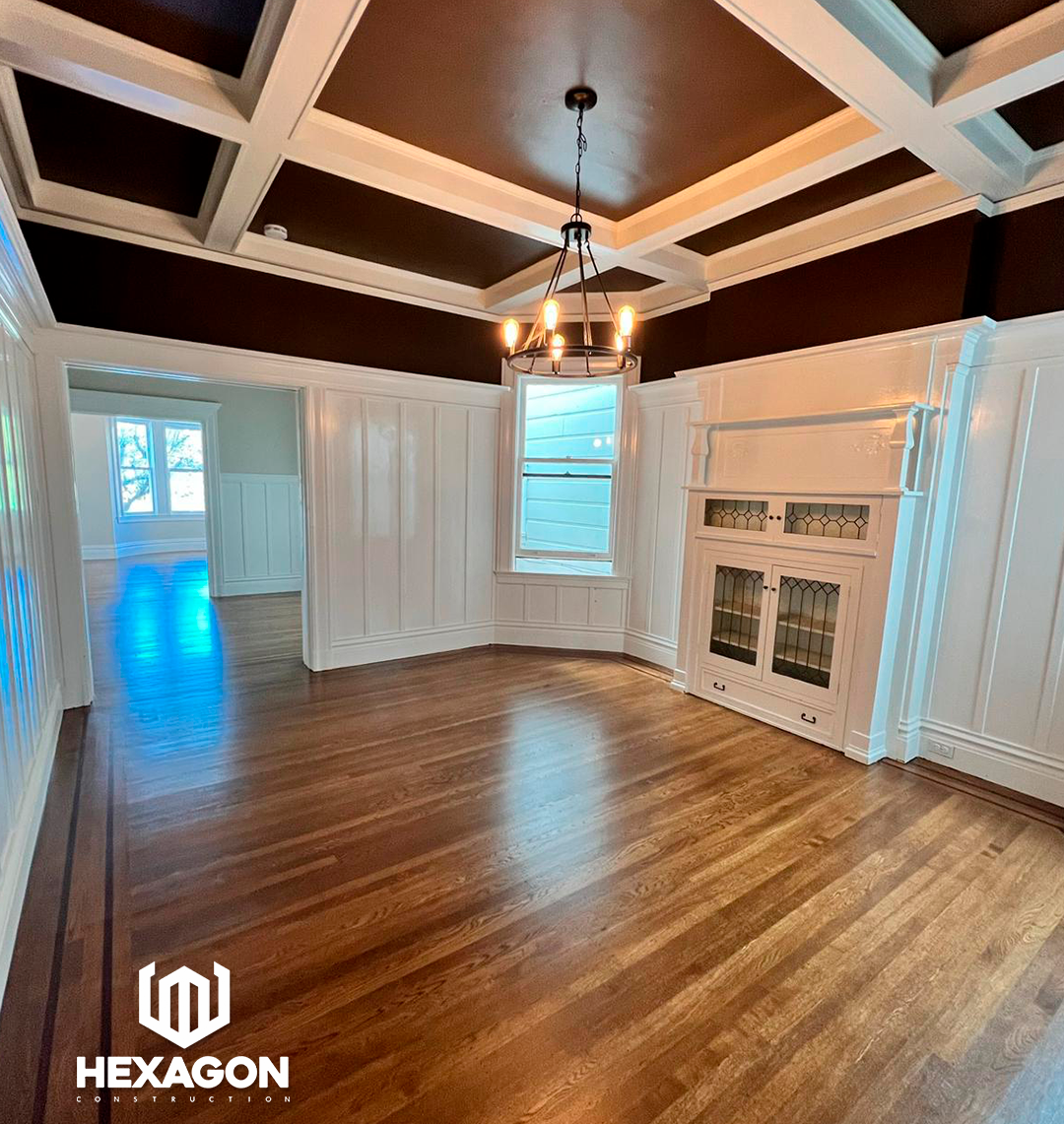 dining room with hardwood floors, white wainscoting, a large window, a vintage-style built-in cabinet, and a chandelier hanging from a coffered ceiling painted in dark brown with white trim. refinished floors, Benjamin paint