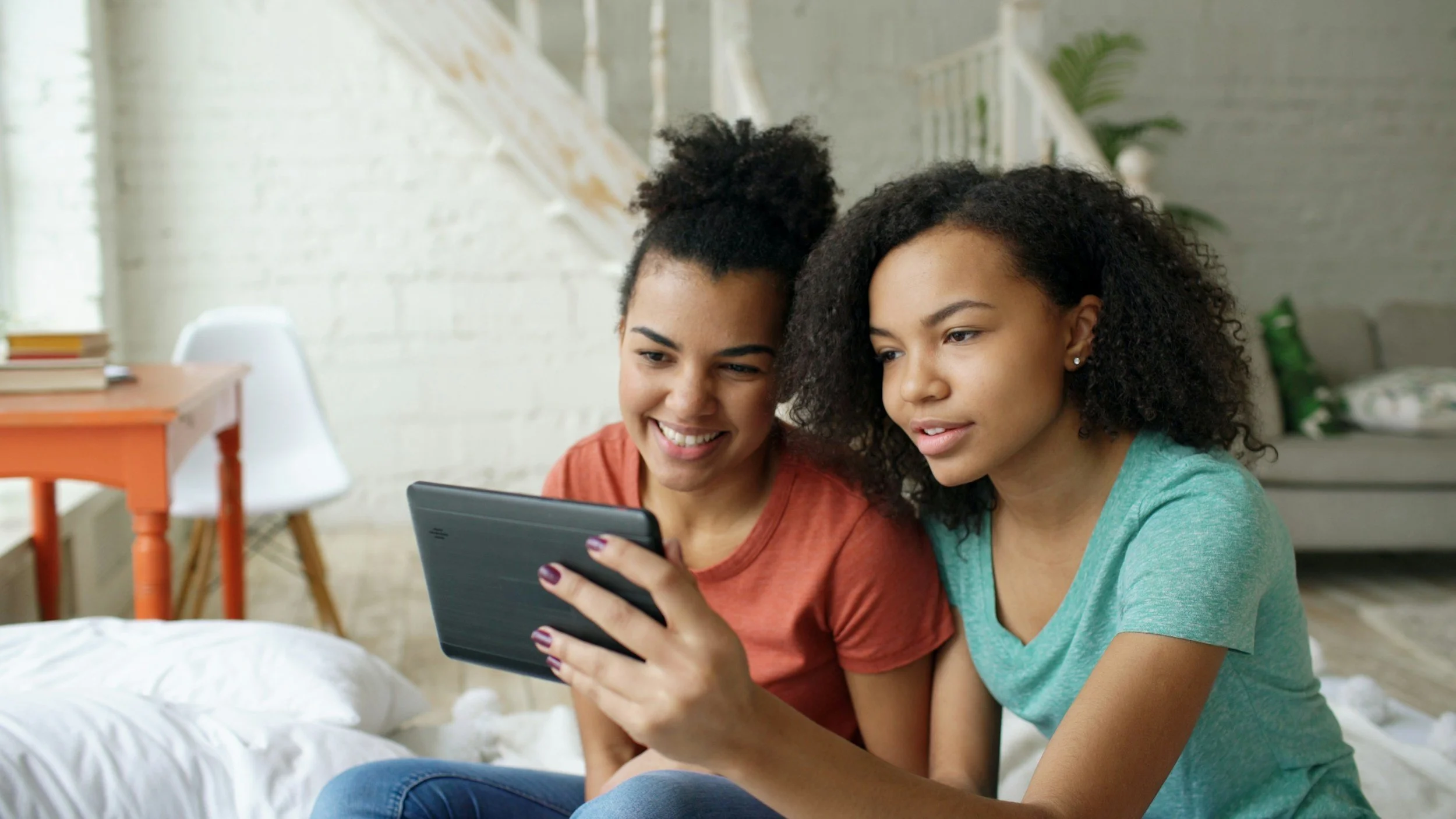 Two friends sitting together with a tablet between them