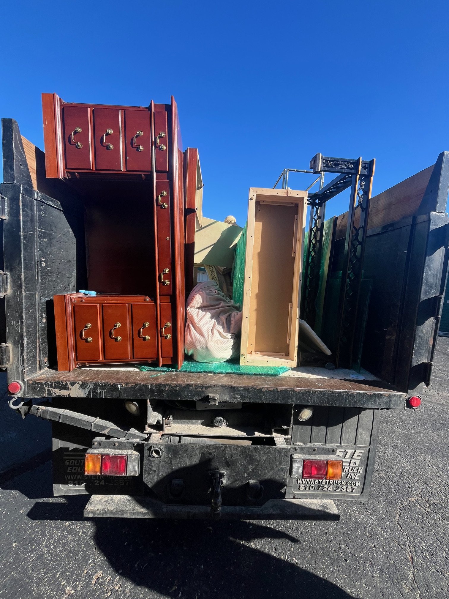 The back of a pickup truck loaded with furniture and other household items during moving or transportation.