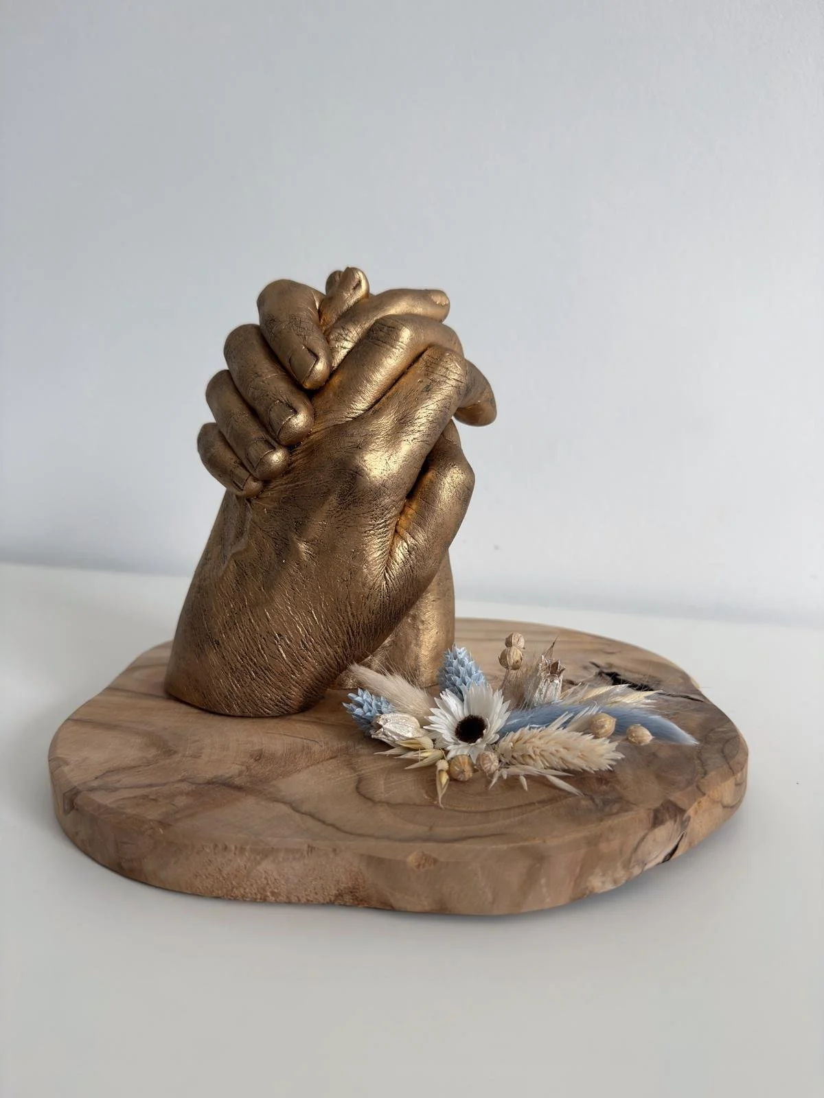 2 handafdrukken van koppel op houten onderlegger met droogbloemen
