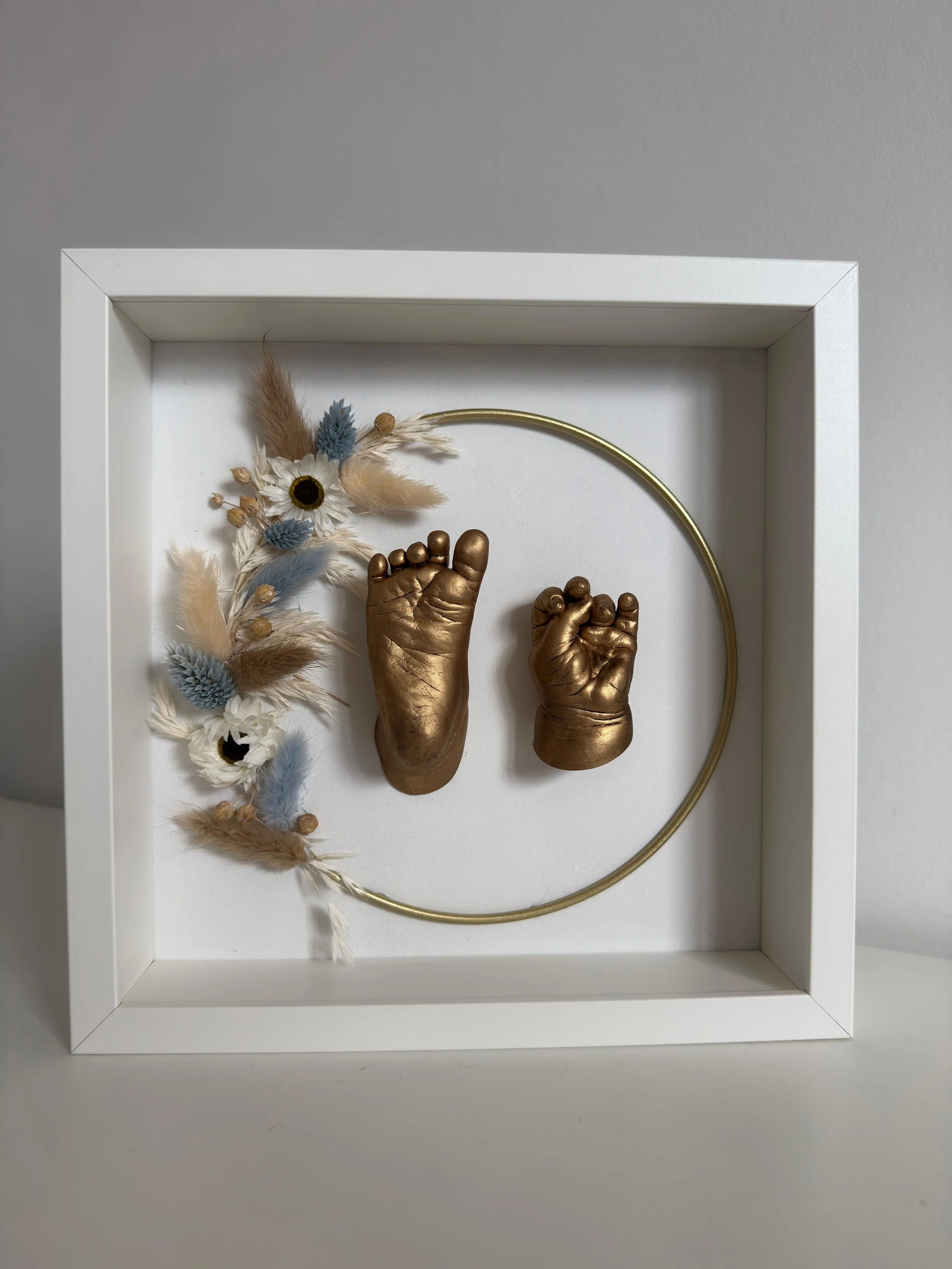 afdruk van baby handje en voetje in witte kader met droogbloemencirkel