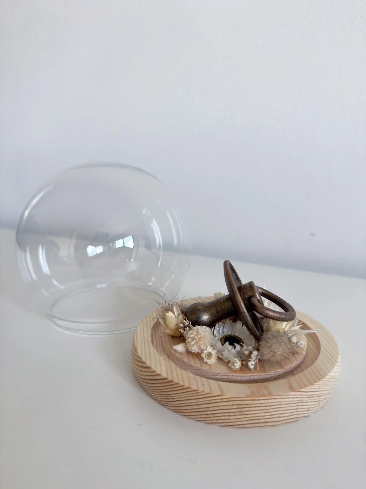 Verbronzing van eerste tutje in bolvormige stolp met droogbloemen