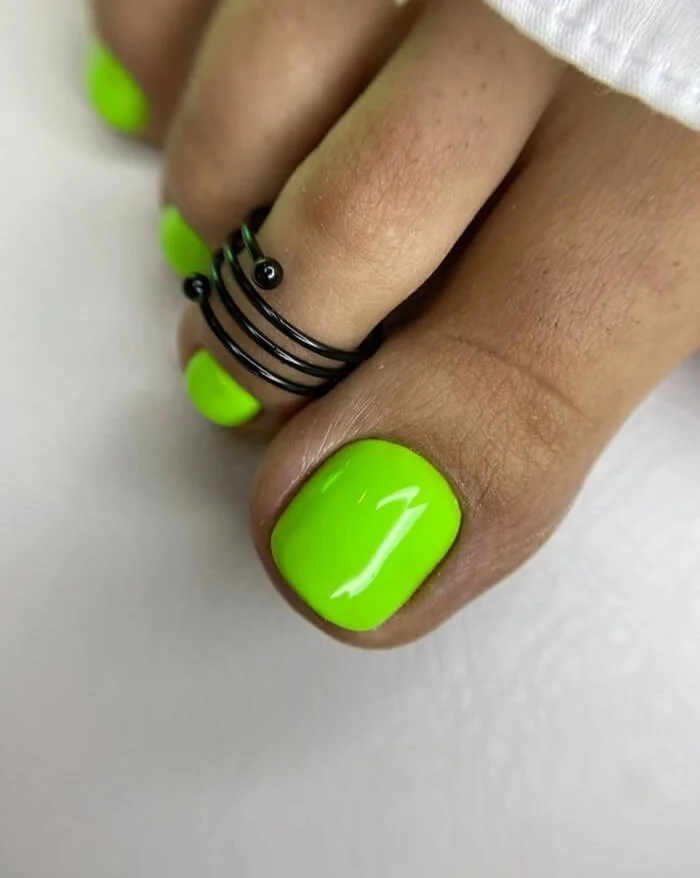 Bright neon green gel pedicure with black toe ring – trendy toenail design in NYC nail salon | Mars Nails