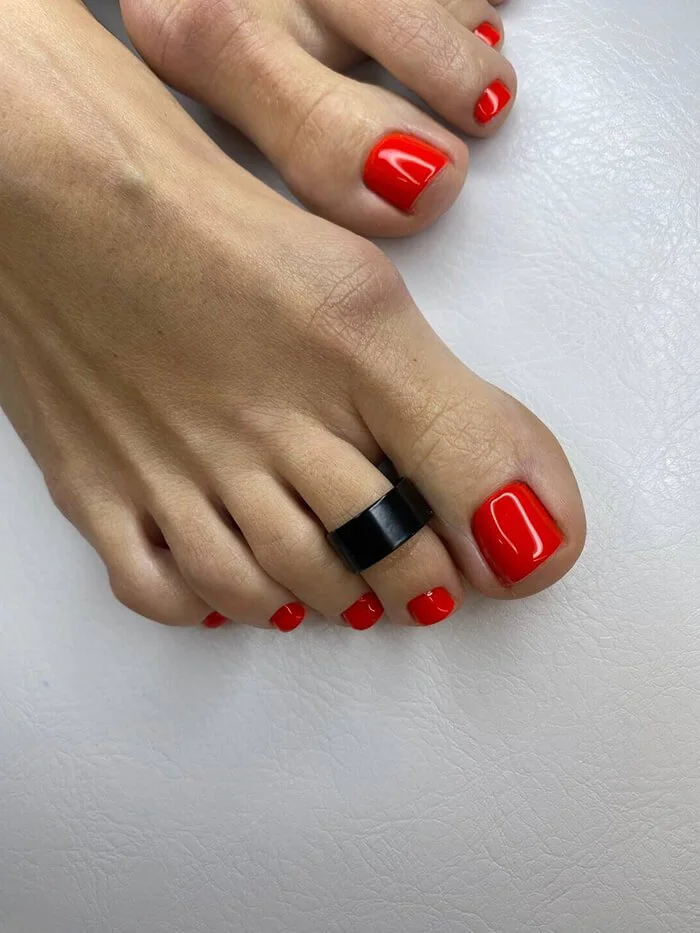 Bold red gel pedicure with black toe ring – modern look from NYC pedicure specialist in FiDi