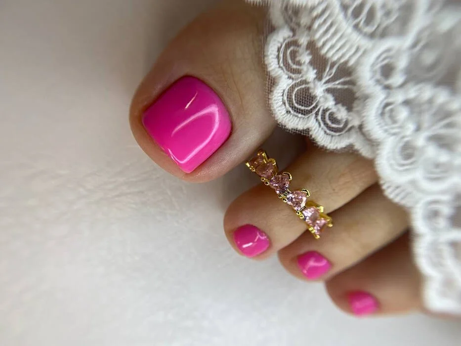Hot pink gel pedicure with gold crystal toe ring – vibrant pedi look in Manhattan nail salon