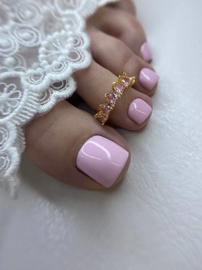 Pale pink gel pedicure with crystal crown toe ring – delicate toenail design at NYC nail salon