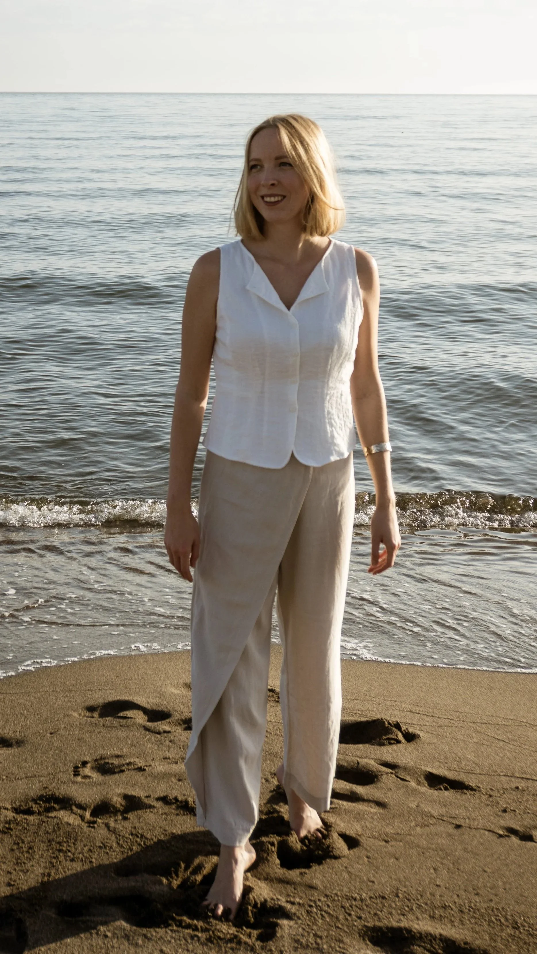 Denise von resovibe steht barfuß am Strand bei Sonnenuntergang – Humanmorphologie als ganzheitliche Betrachtung von Kopf, Körper, Ausdruck und Charakter, keine Physiognomie und kein Face Reading.