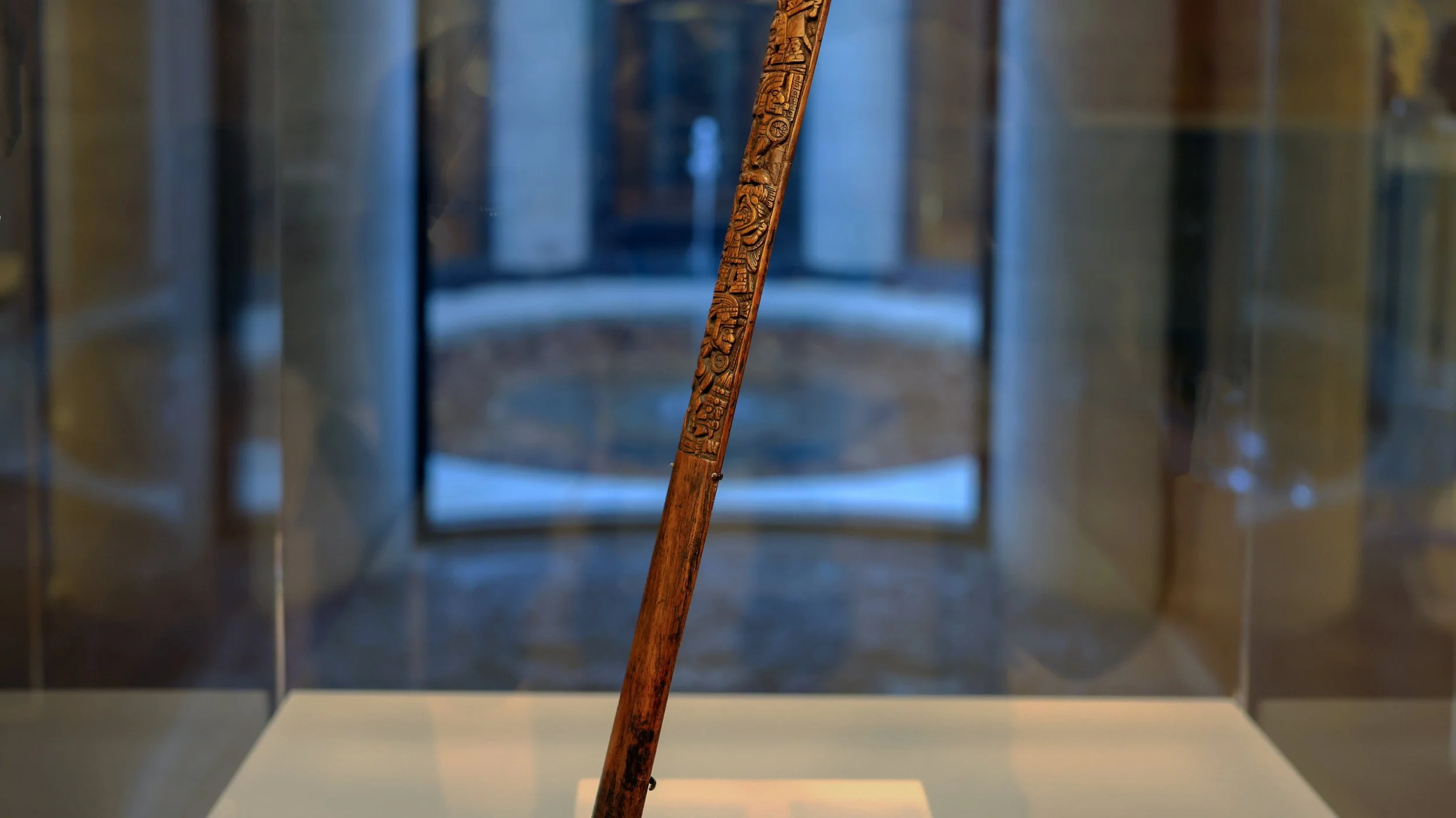 A wooden stick has elaborate carvings on one end