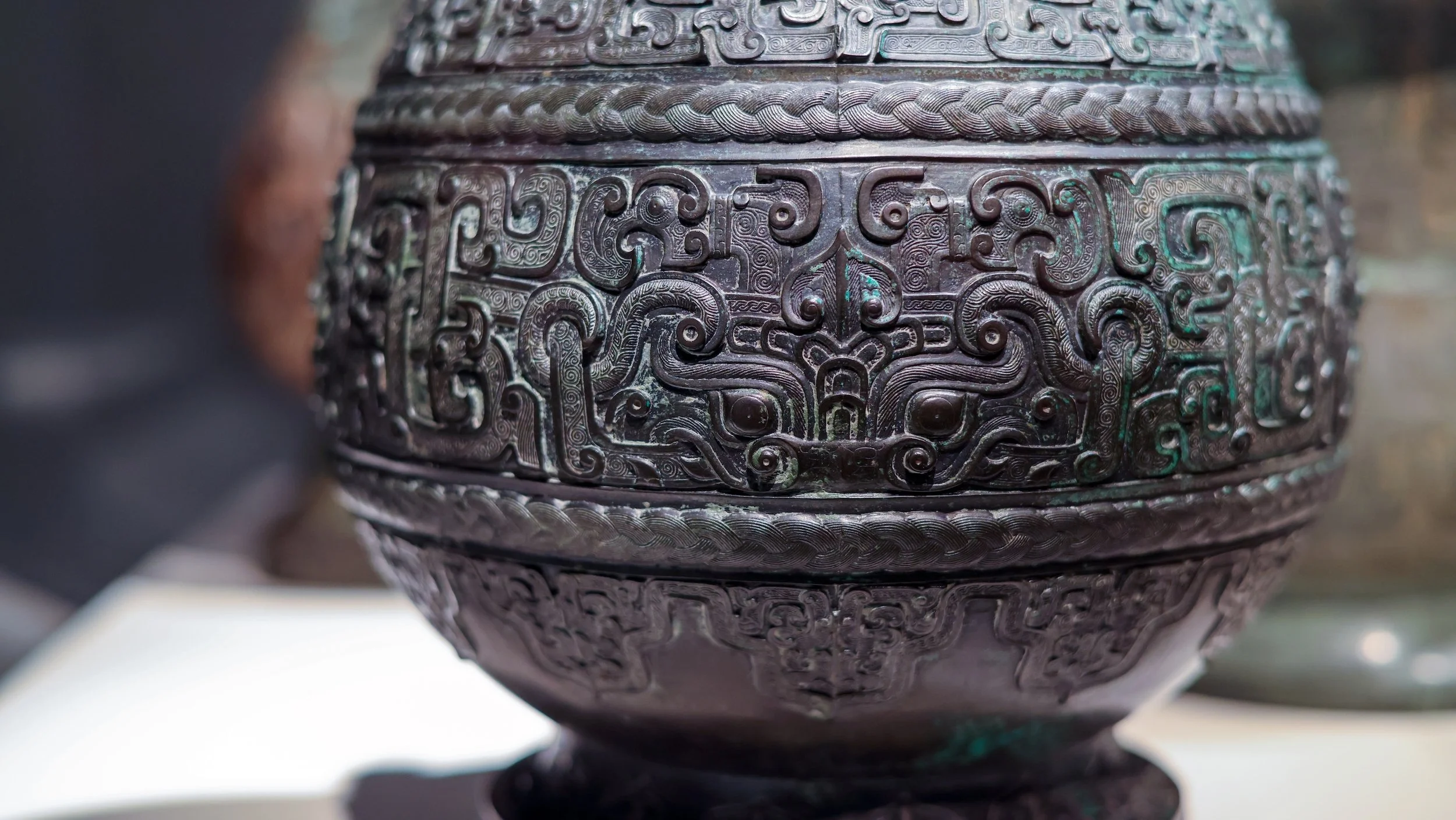 interlaced forms sprawl across the bulbous surface of a bronze vessel