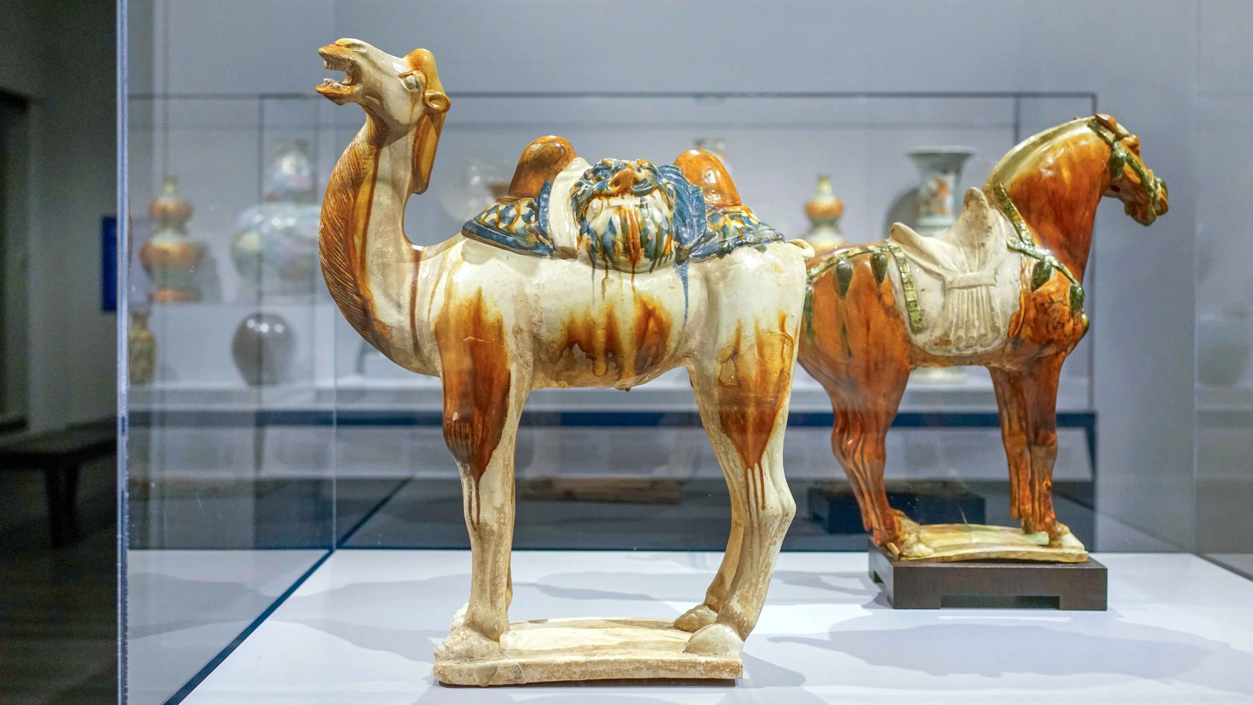 A ceramic sculpture of a camel with a warrior riding on its back, displayed in a museum.