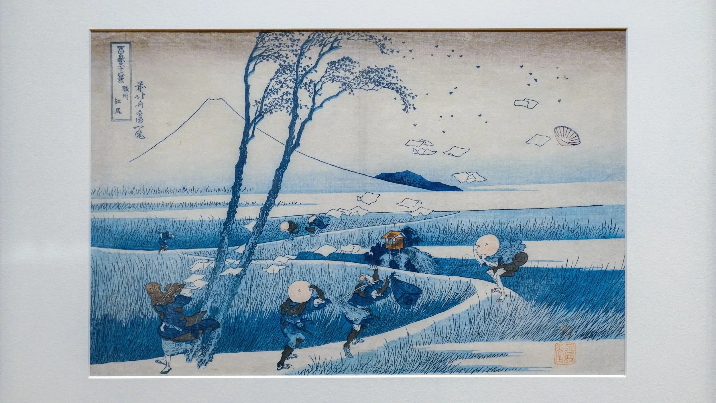 Figures travel through a windy blue landscape with Mt. Fuji in the distant background