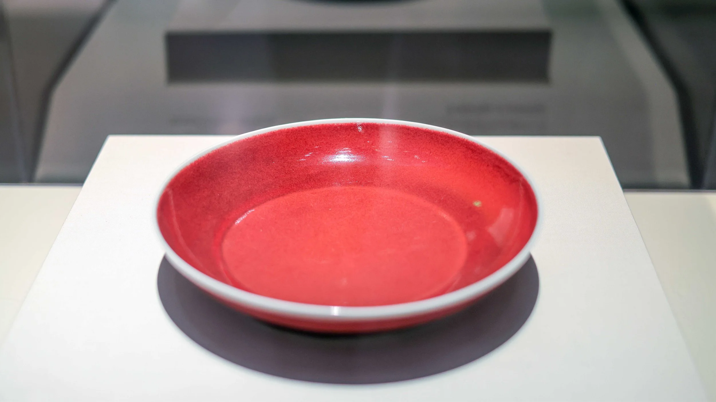 Red ceramic bowl with a glossy finish, placed on a white surface.
