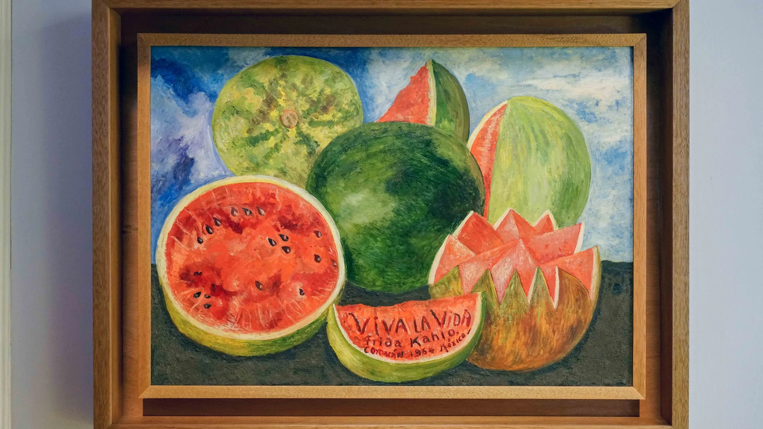 a still life painting showing watermelons arranged on a ground and cut into different shapes