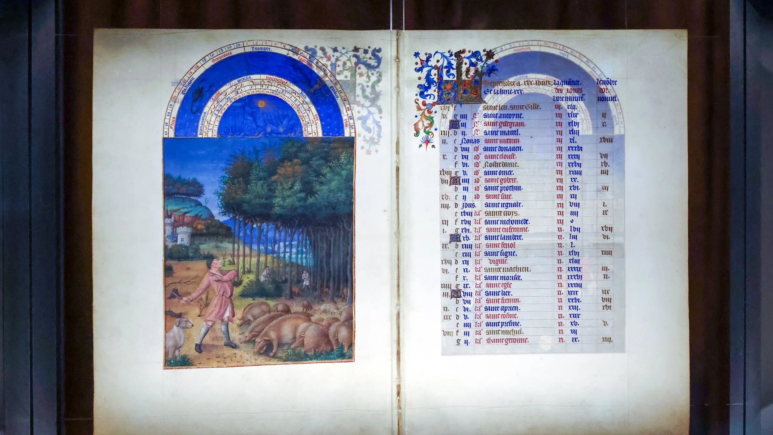 Two pages are open in a manuscript with one showing a colorful scene of a forest with a pig farmer tending to a group of pigs eating acorns