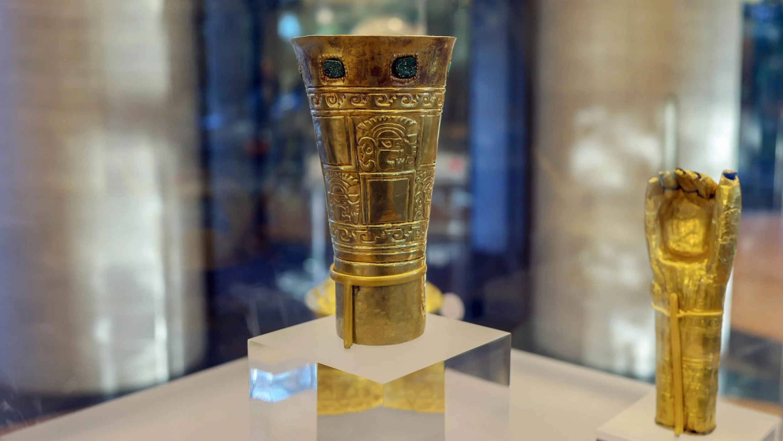 A golden beaker stands in a museum case