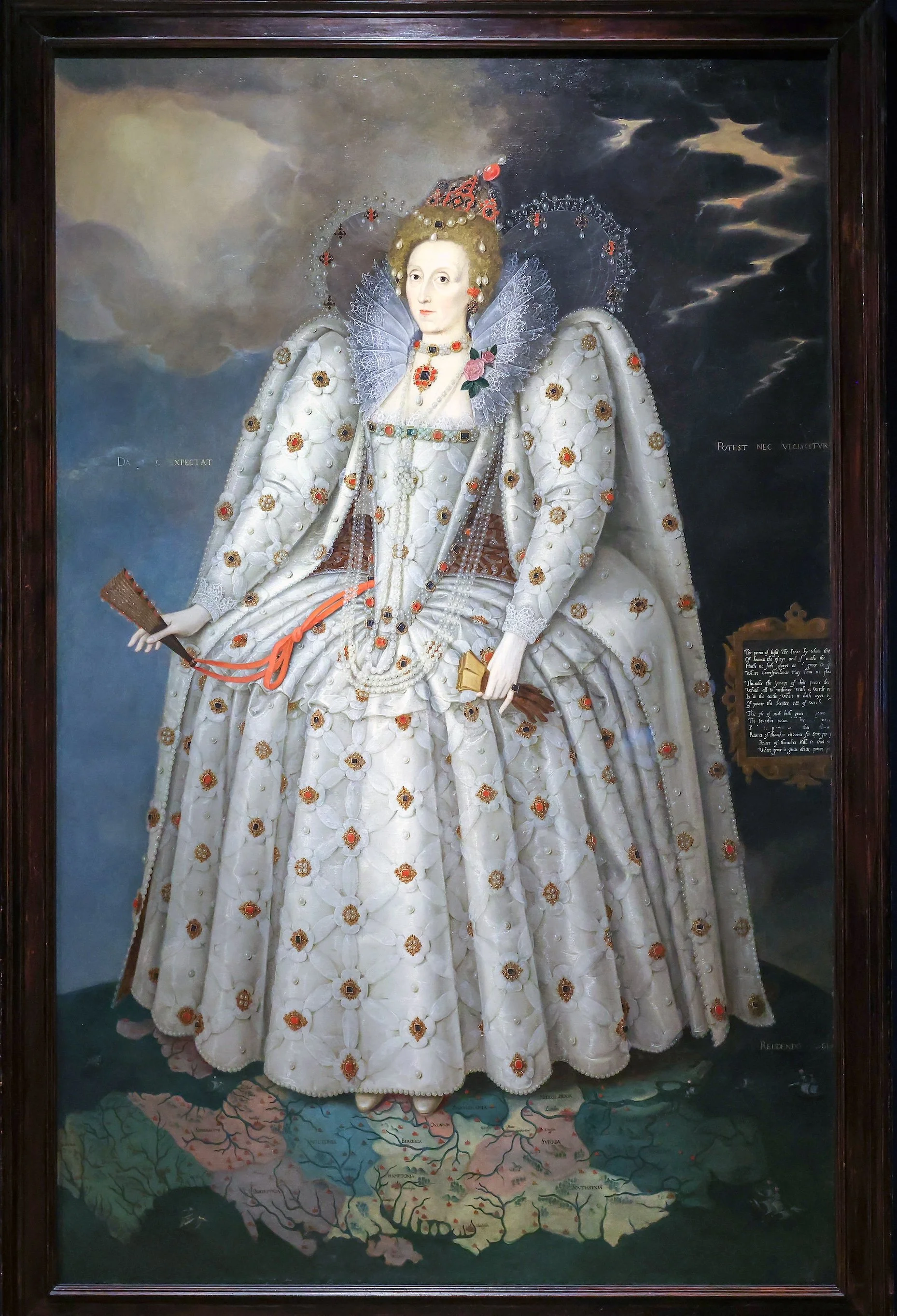 A portrait of a woman dressed in an elaborate, ornate white gown decorated with flowers and pearls, holding a fan, with a dark cloudy sky background and a map of America at her feet.