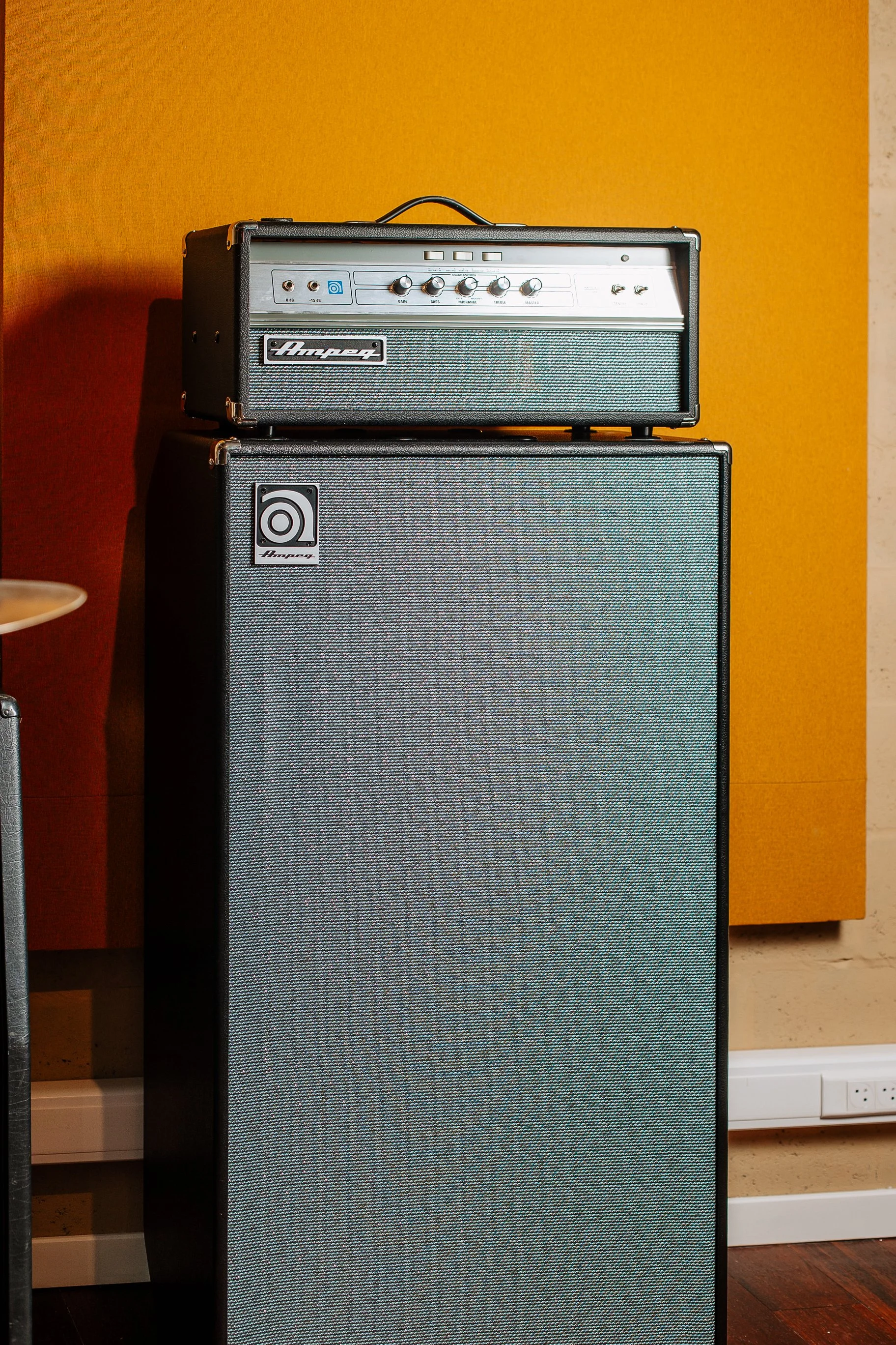 Amplificateur et enceinte de musique dans une pièce avec mur orange et sol en bois.