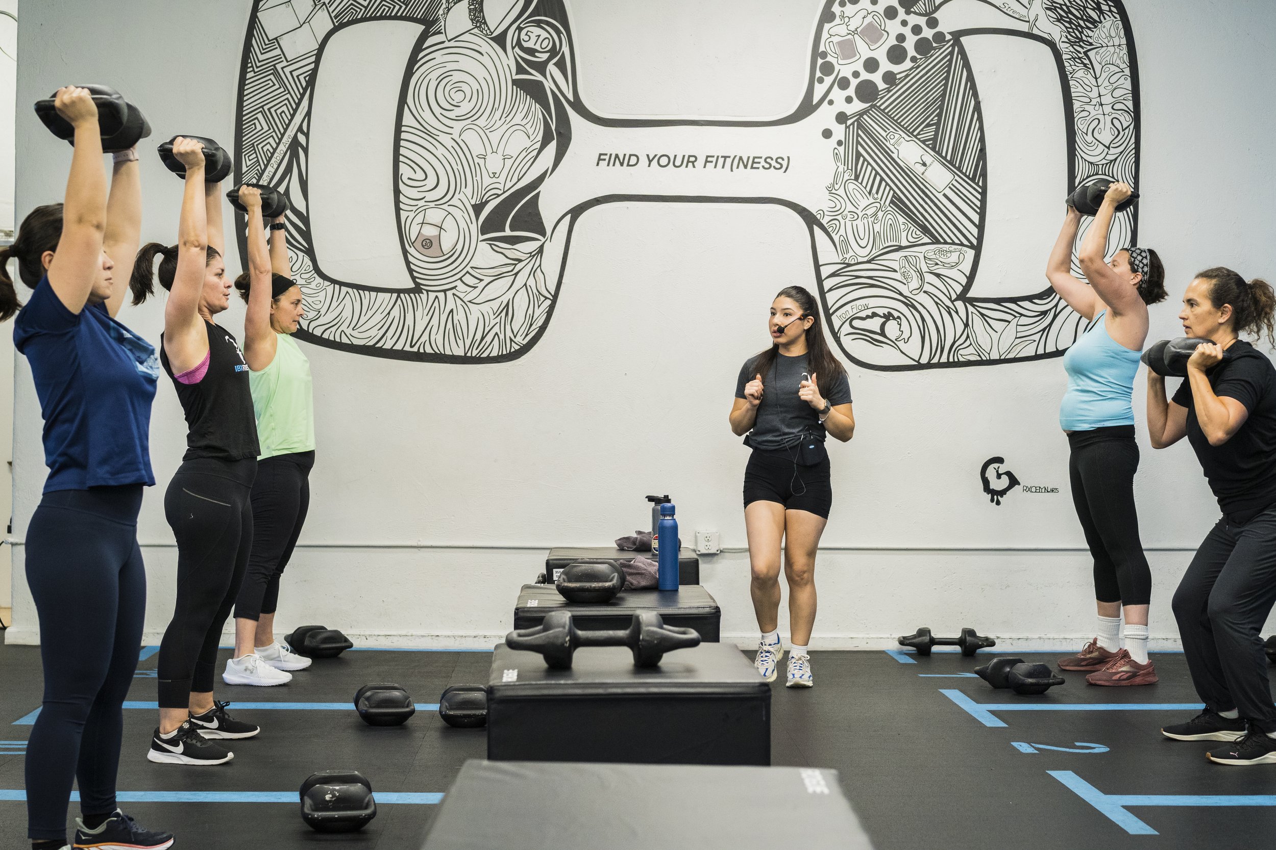 Picture of a full IBX Fitness class with members and a coach  working through a strength workout
