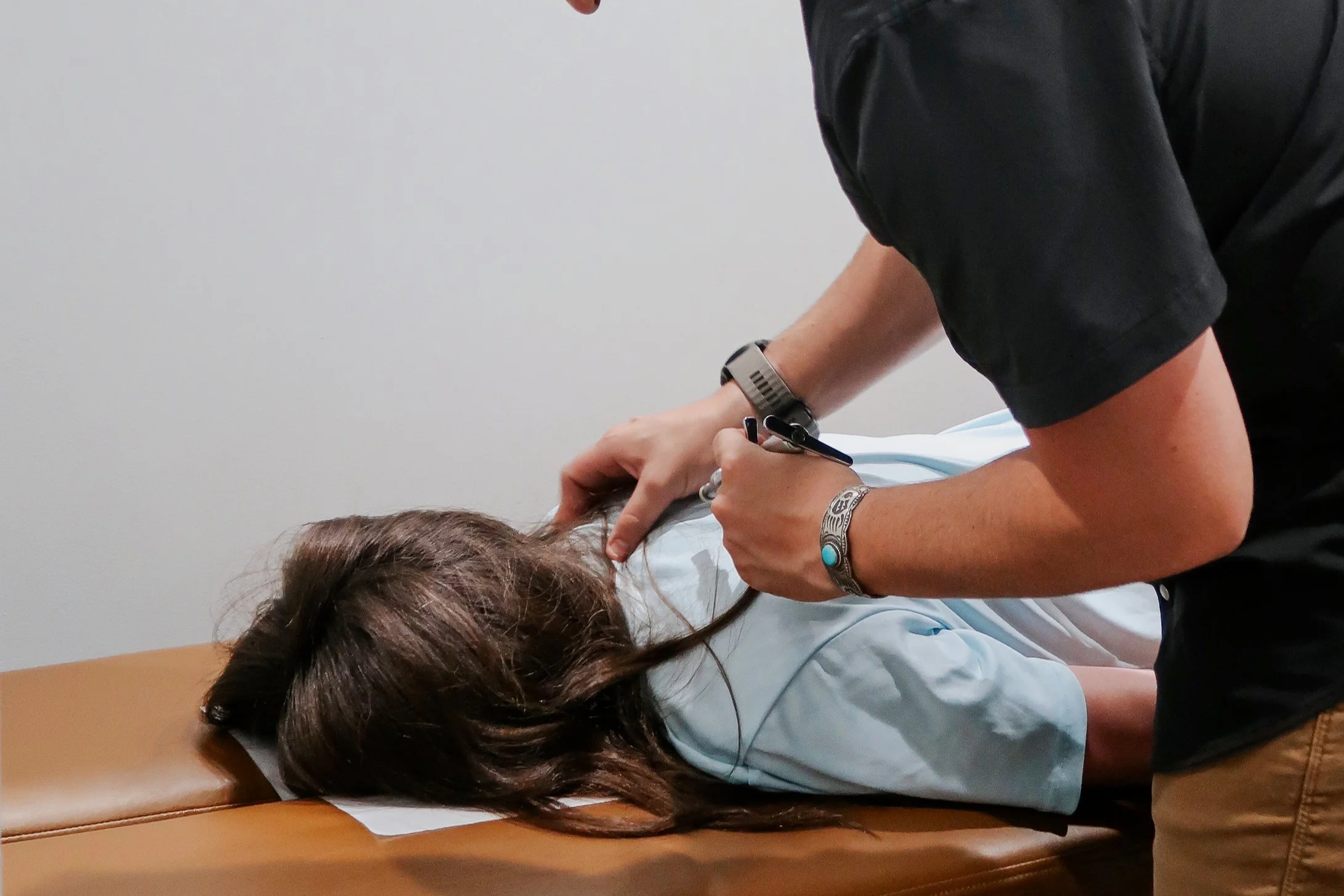 Chiropractor adjusting a patient's upper back with an adjusting instrument at Invictus Chiropractic in Cypress, TX