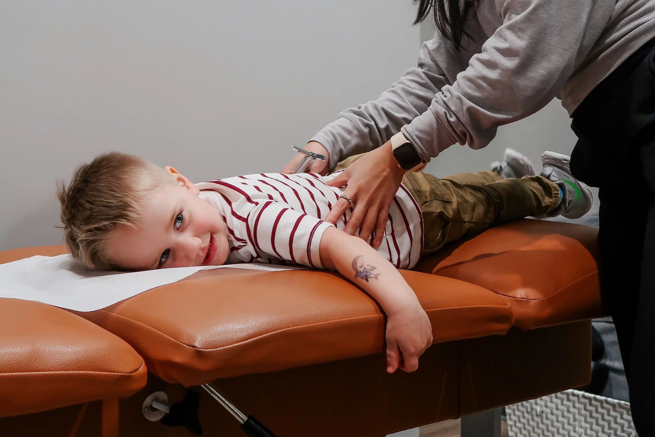 Smiling young boy receiving a gentle pediatric chiropractic adjustment in Cypress, TX