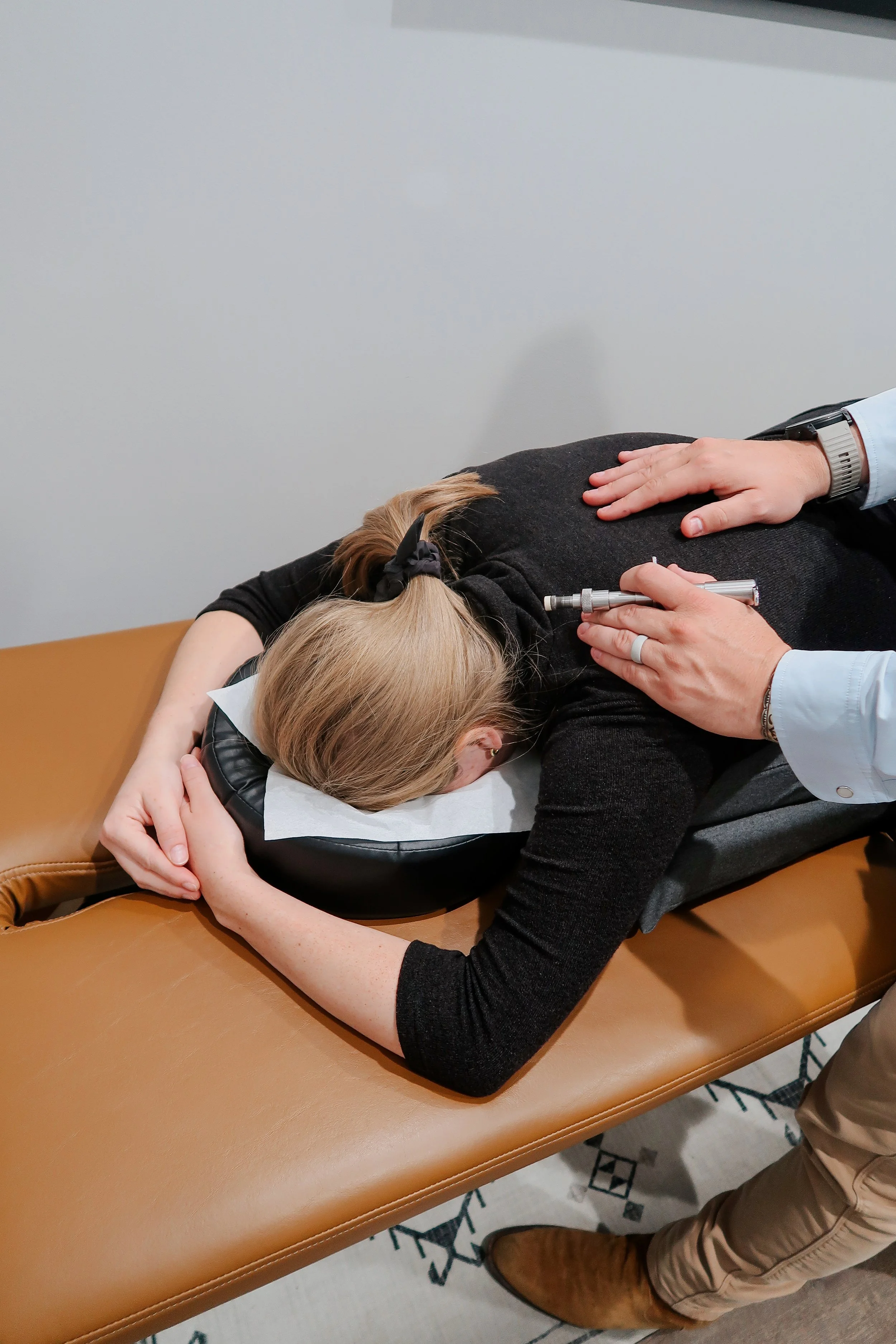 Gentle instrument-assisted chiropractic adjustment for a mom at Invictus Chiropractic in Cypress, TX