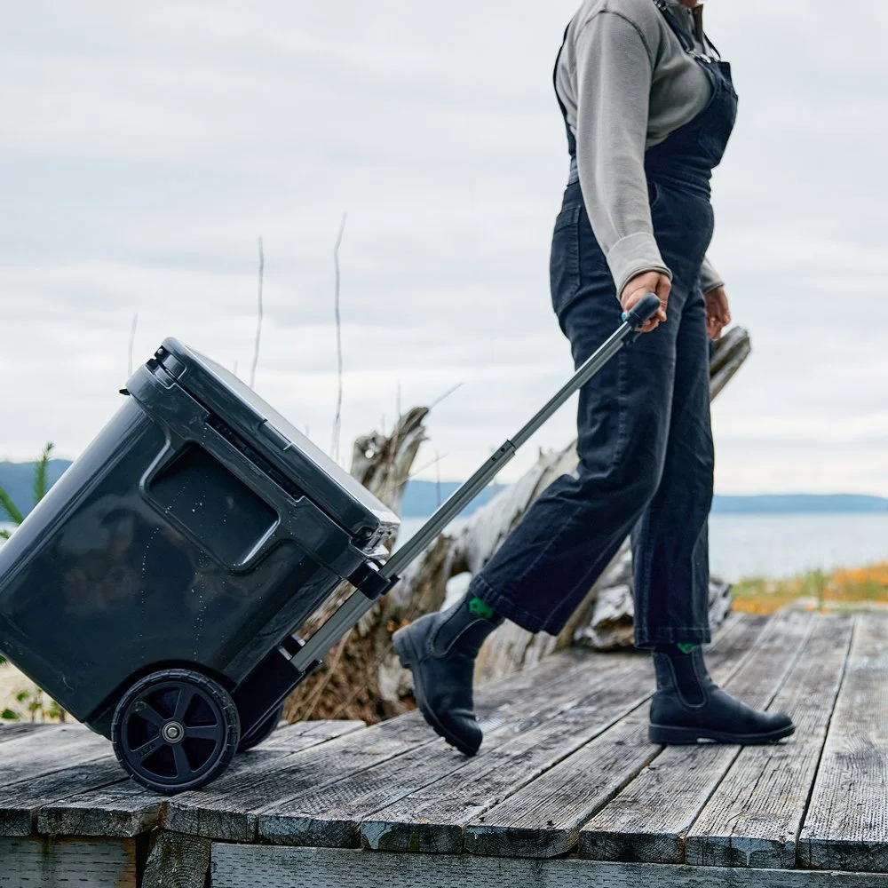 Person walking on wooden boardwalk pulling a YETI rolling cooler.