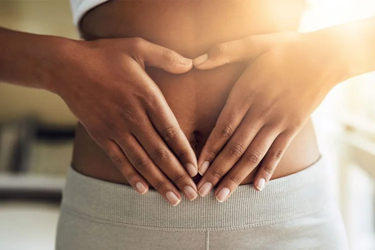 Hands forming a heart over the belly, representing gut health
