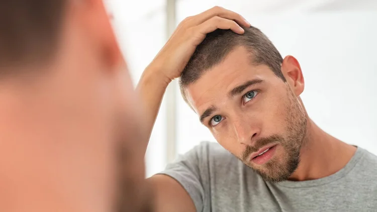 Man concerned about thinning hair, representing hair loss treatment