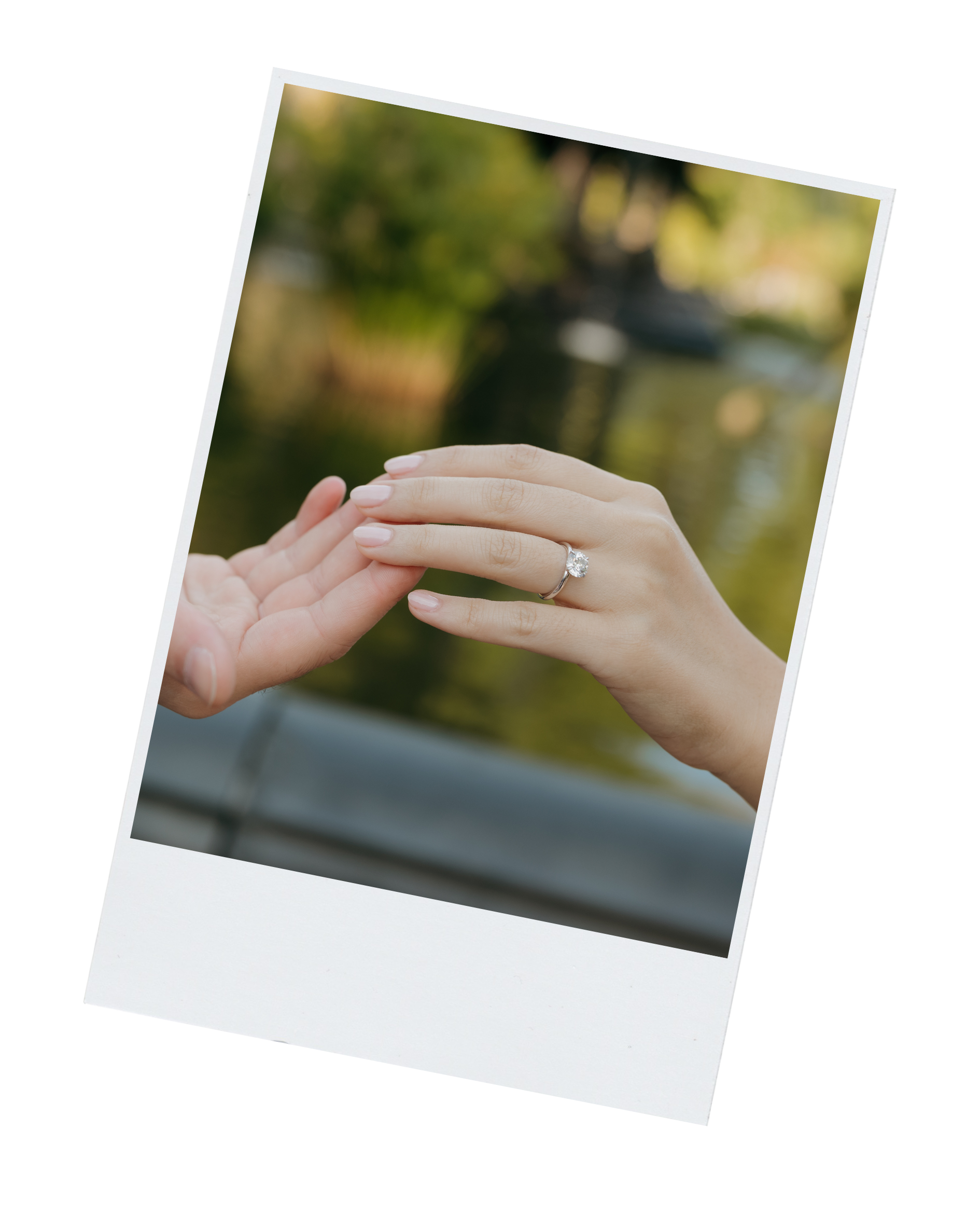 DC Wedding Photographer Close-up of a woman’s hand with a diamond engagement ring, touching a child's hand outdoors near water and trees.