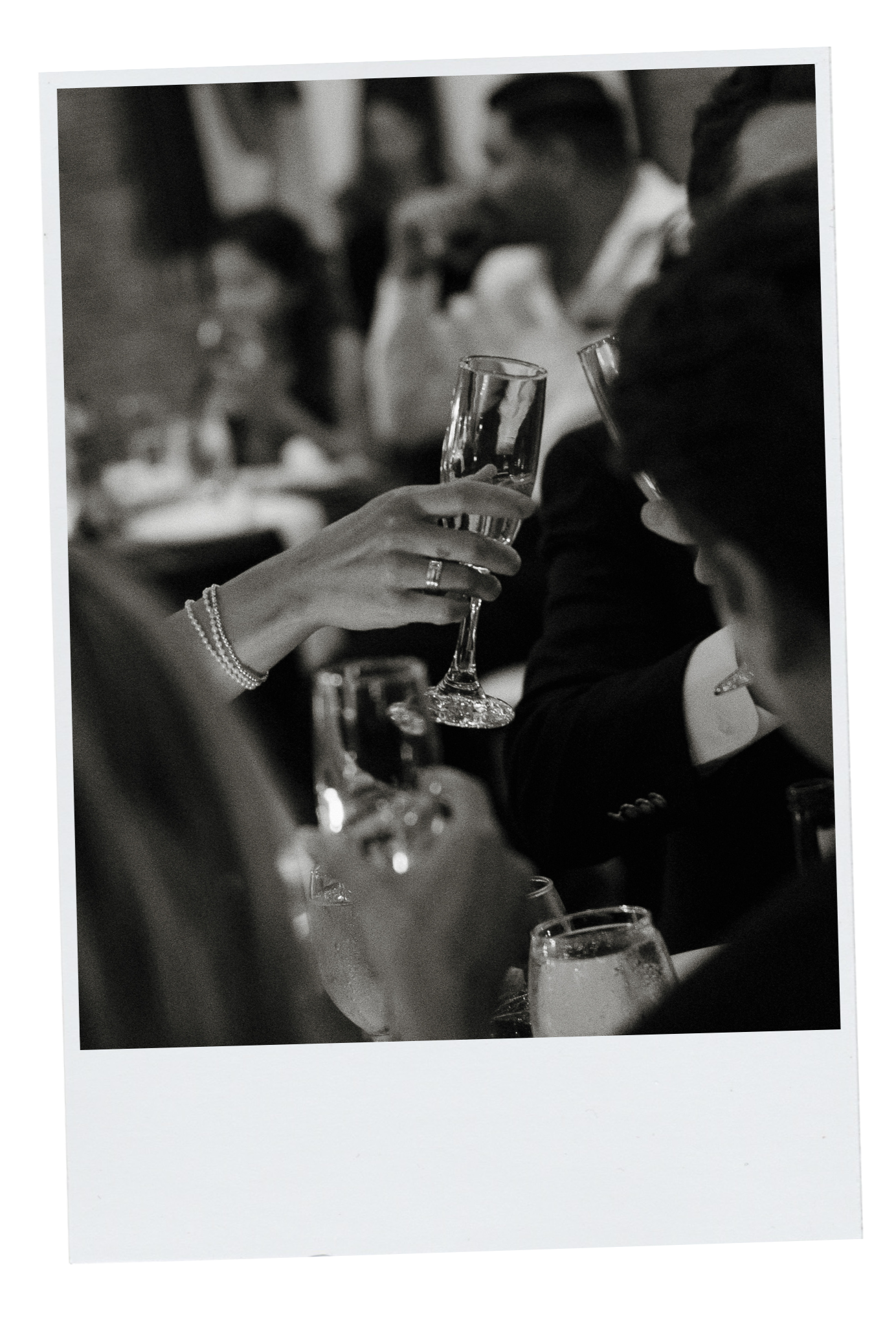 Black and white photo of people at a formal event clinking champagne glasses, dressed in suits and elegant attire. DC Wedding Photographer