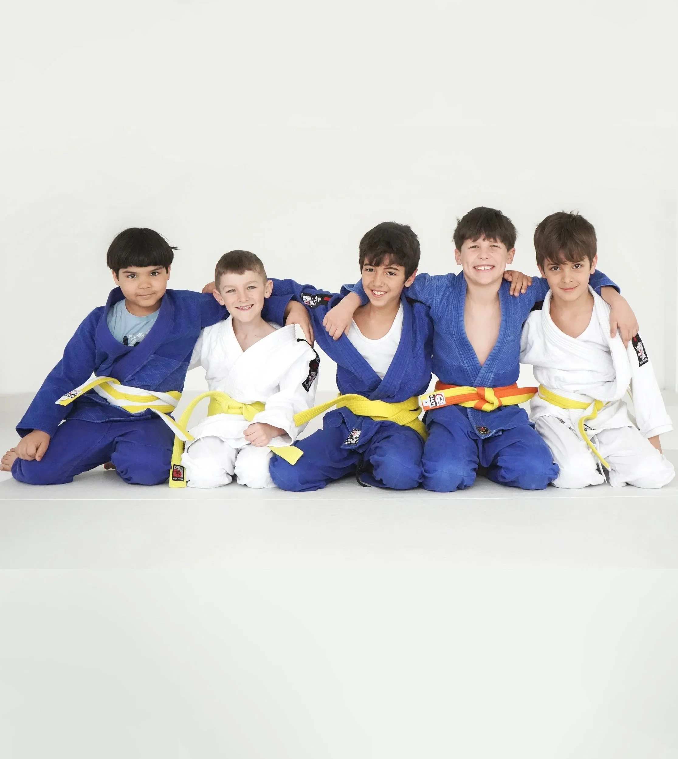 Deux enfants pratiquent le judo dans un dojo, une en gi rose et l'autre en gi blanc et ceinture jaune.