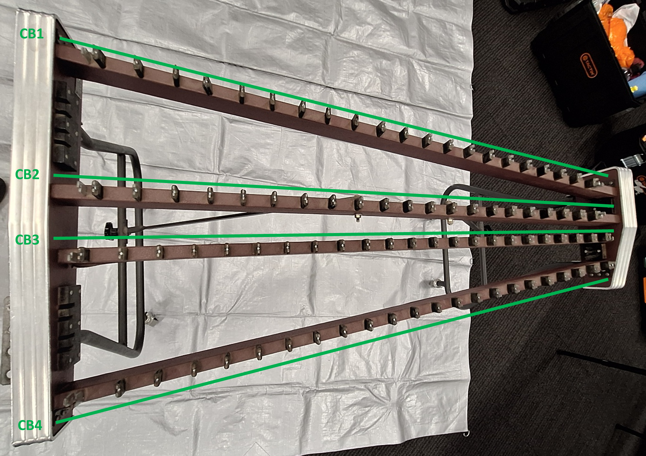 Overhead shot of a xylophone frame (bars and resonators removed). Green lines highlight the four crossbeams.