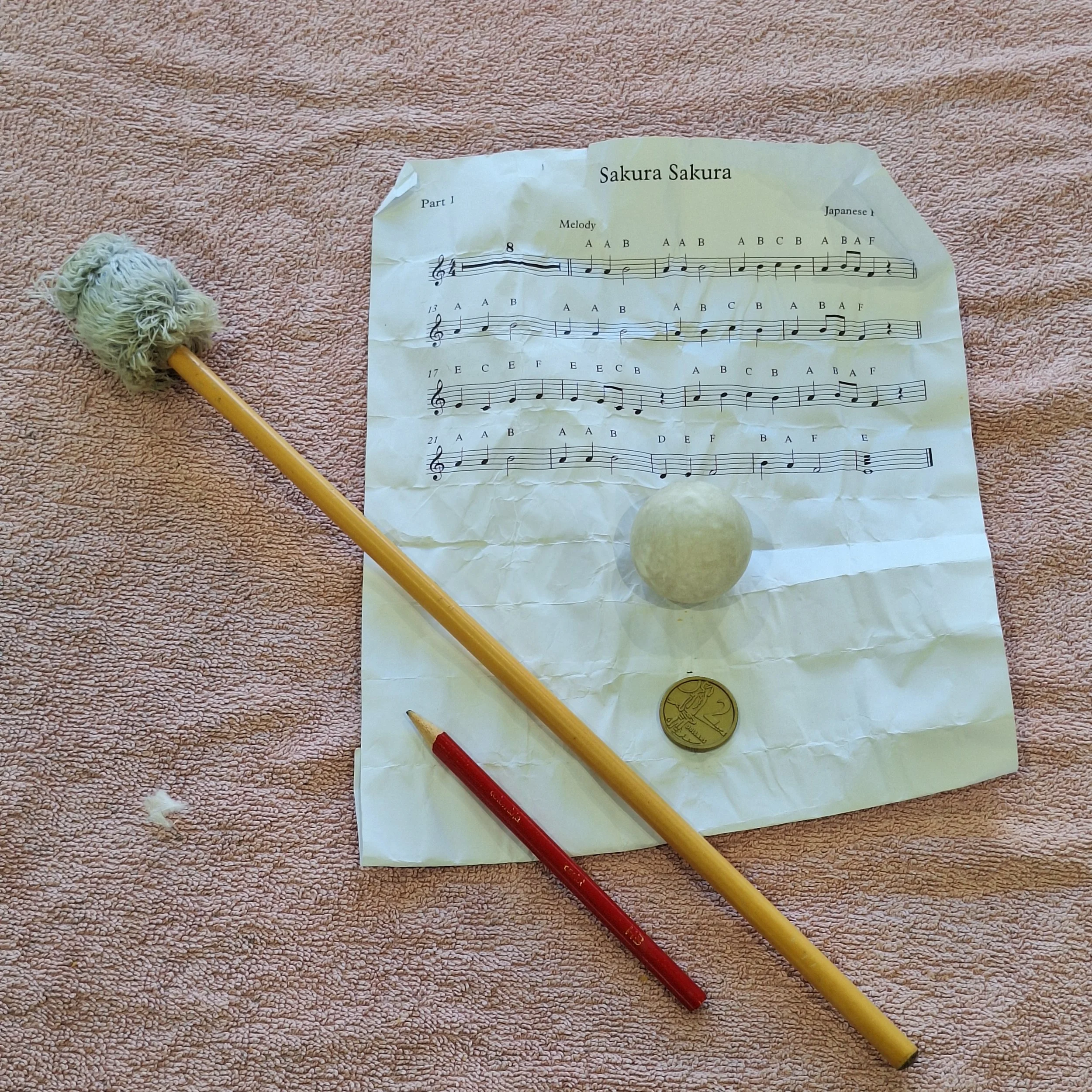 The most recent collection of finds from a marimba: Sakura Sakura sheet music, a mallet, a pencil, a ball, and fake $2 coin.