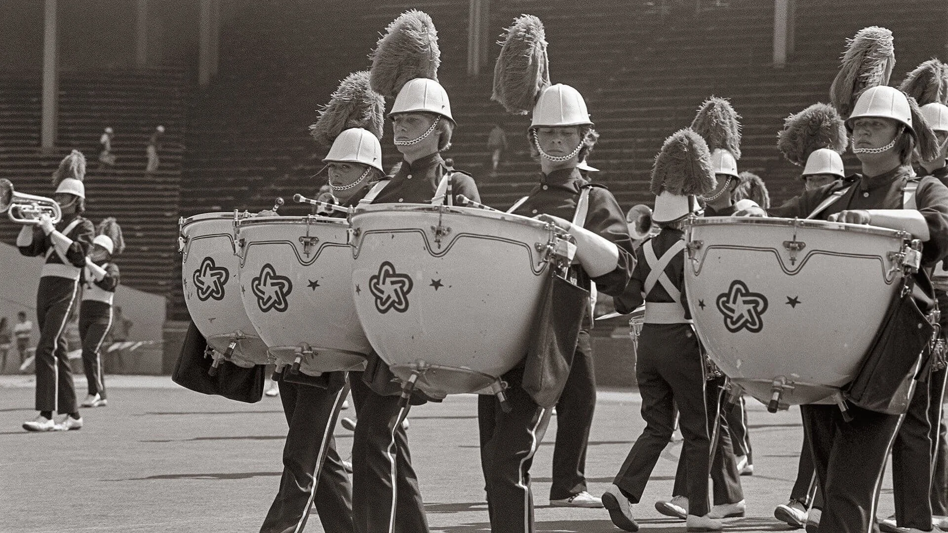 Black and white picture of four timpanists for the Blue Stars at the Drum Corps International Whole Championship, 1976. The drums are on harnesses and do not have pedals.