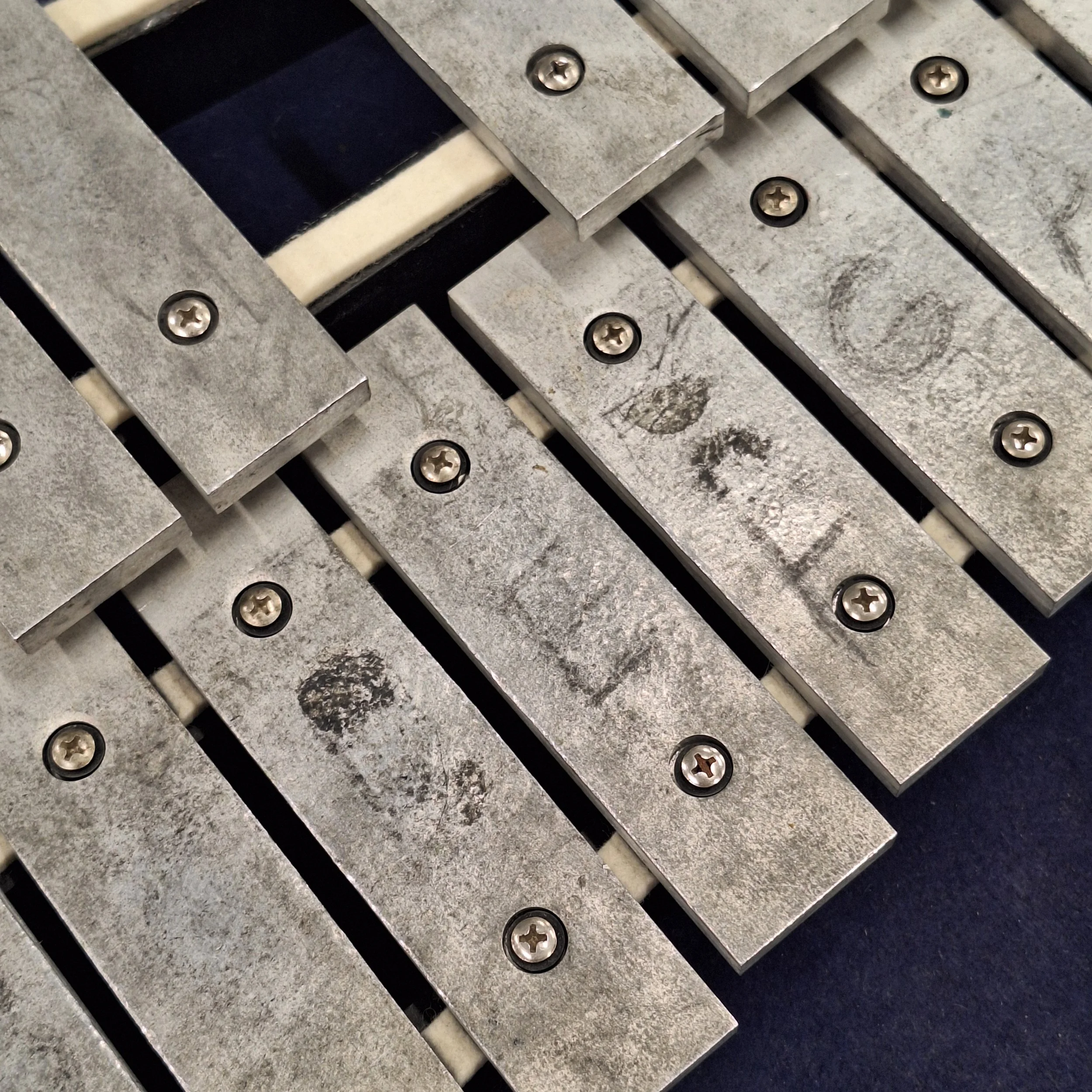 Dirty glockenspiel bars. Note names have been etched in with pencil and there’s evidence of both stickers and blue marker pen.