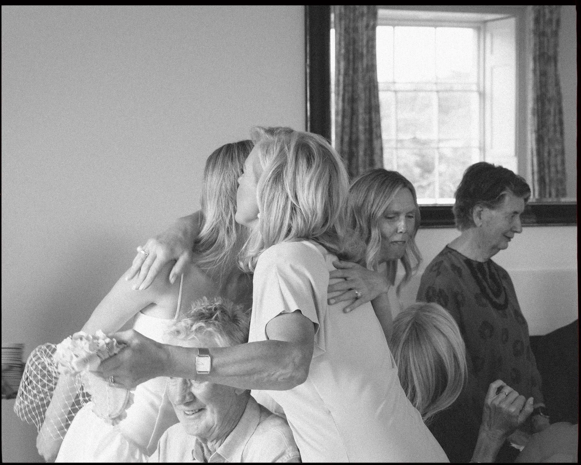 Black and white 35mm film wedding photograph of emotional bridal preparation, candid documentary moment