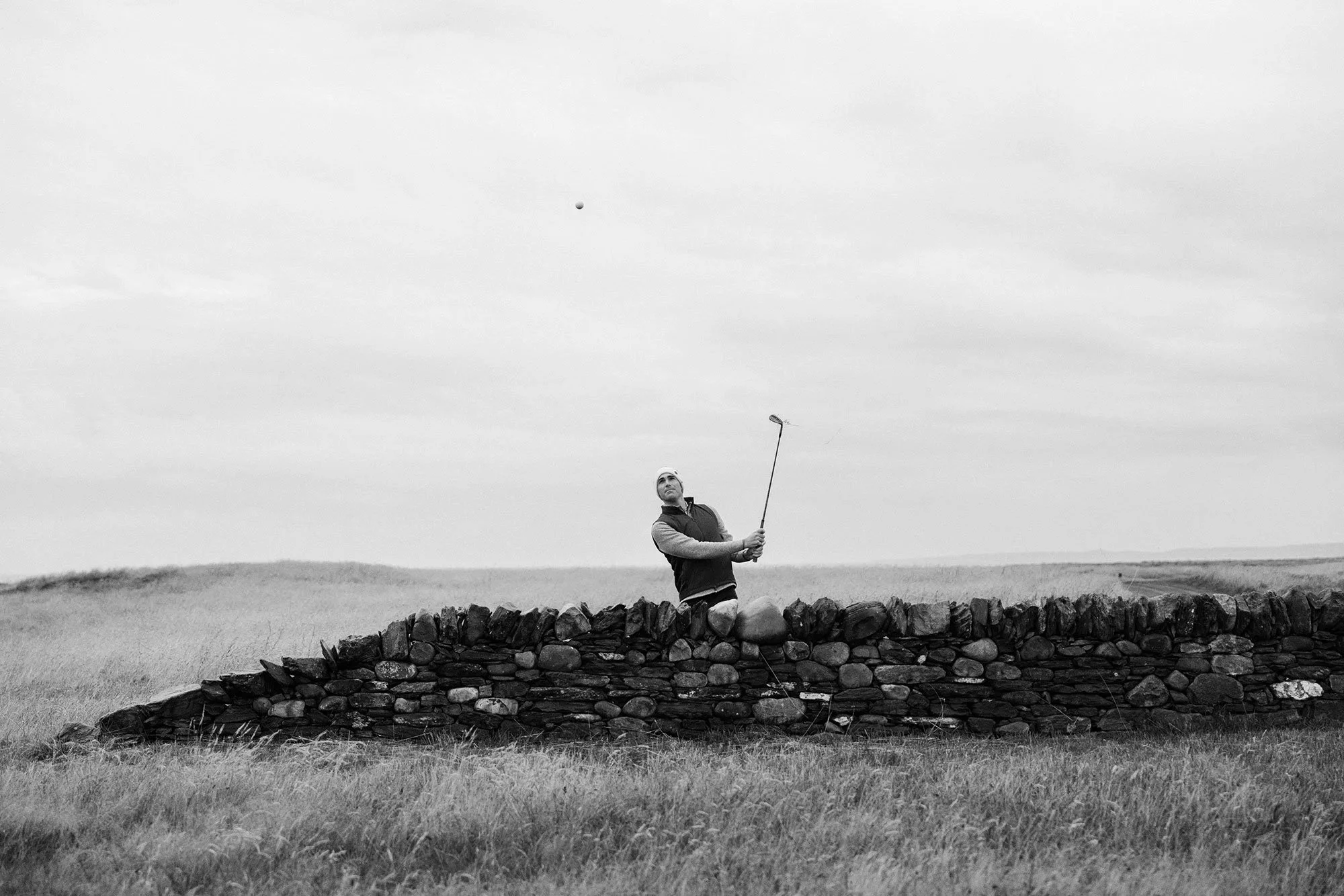Golfer chipping over the wall at the Machrie Golf Course in Scotland