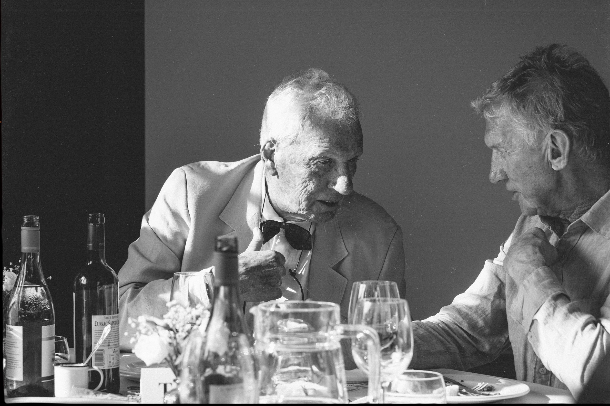 Black and white documentary wedding photograph on film, an intimate table conversation during the reception